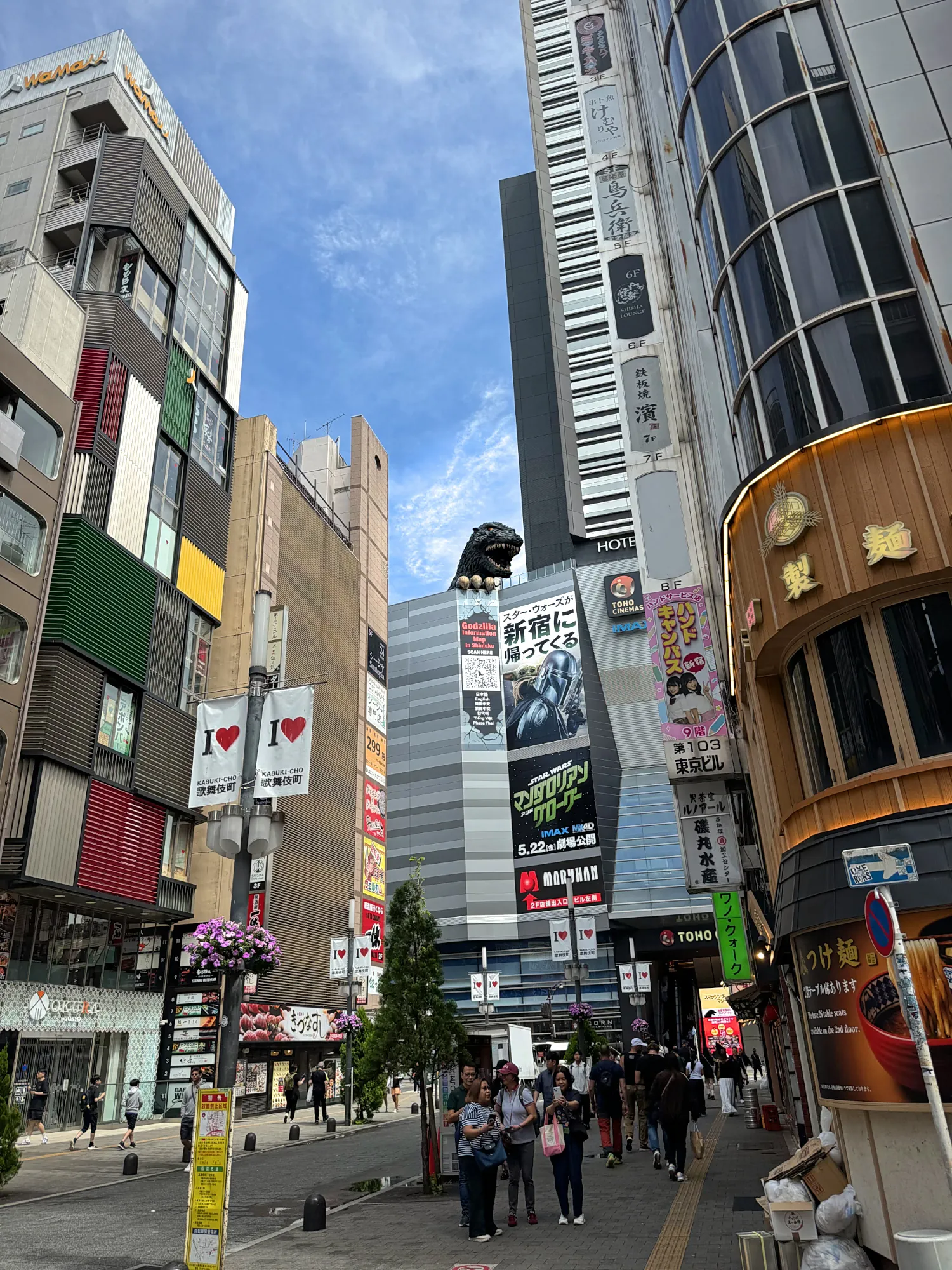 The Godzilla head looking down over a busy Kabukicho street lined with signs in Shinjuku, Tokyo.