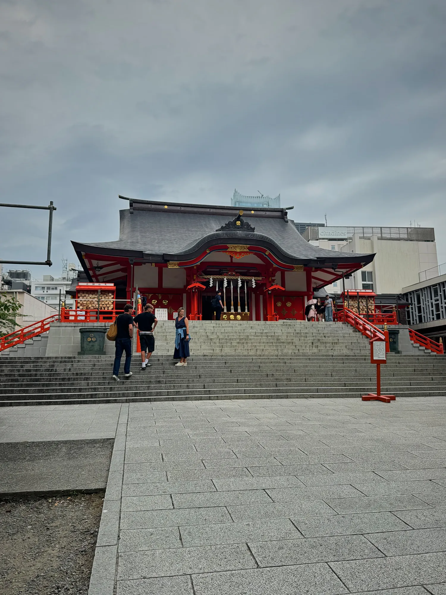 The red main hall of Hanazono Shrine in Shinjuku, Tokyo, at the top of a wide stone staircase.