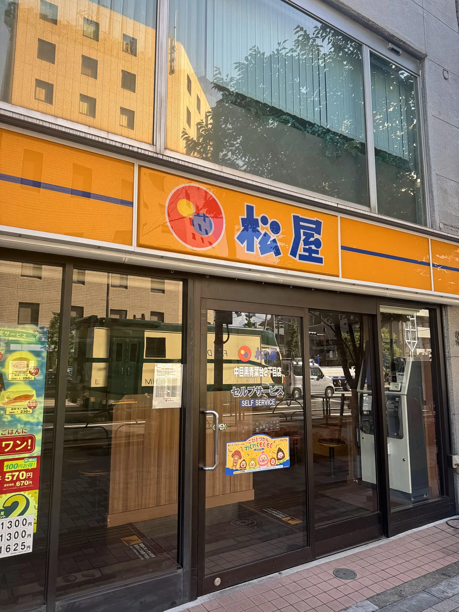 The orange Matsuya sign and glass front of a Matsuya gyudon restaurant in Tokyo.