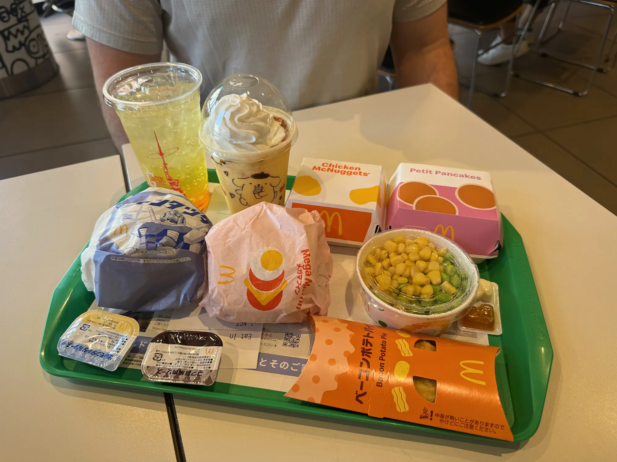 A McDonald's Japan breakfast tray with a Chicken Tatsuta, a Mega Muffin, Petite Pancakes, Chicken McNuggets, corn and edamame, a Bacon Potato Pie, a Pompompurin Frappé, and a McFizz at a McDonald's in Shinjuku, Tokyo.