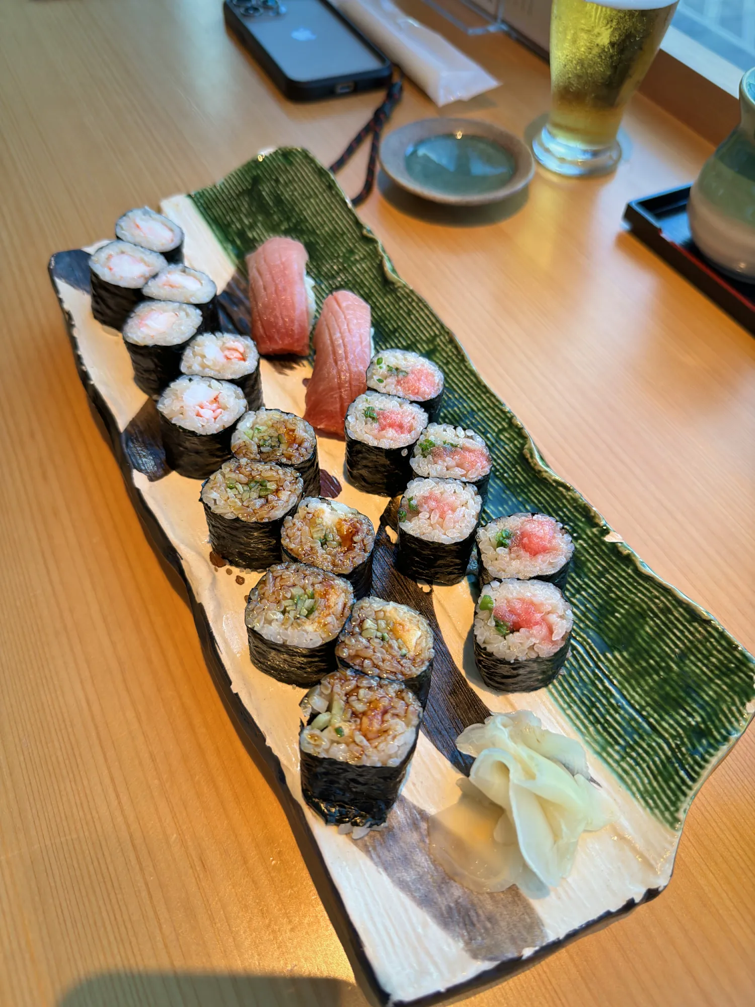 A long platter of assorted sushi rolls with pickled ginger at a restaurant in Narita Airport.