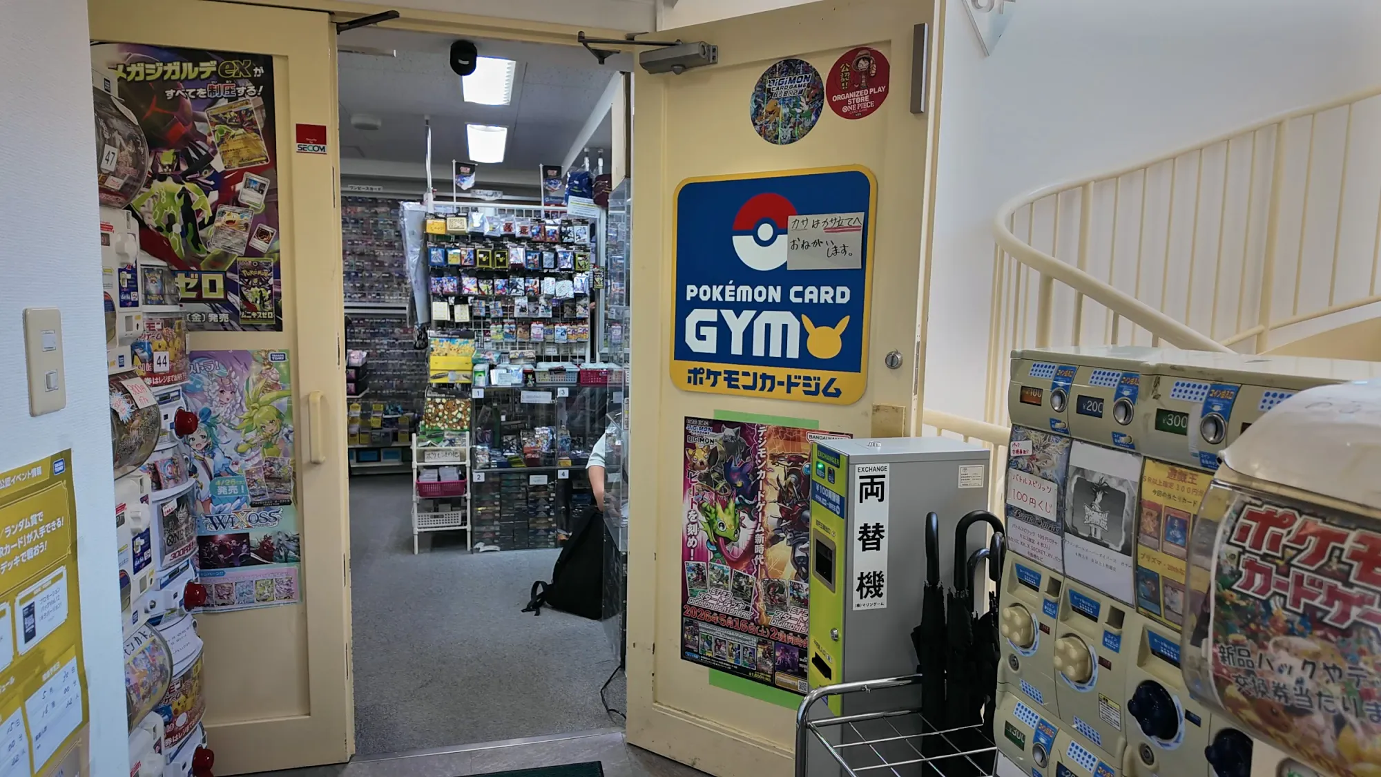 The entrance to a Pokémon card shop in Tokyo with a Pokémon Card Gym sign on the door and shelves of cards inside.