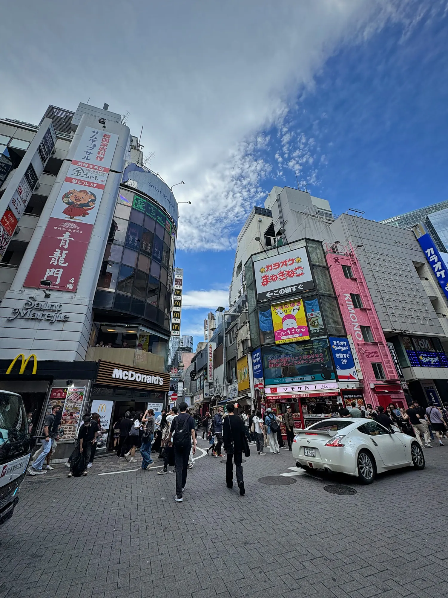 A crowded street corner in central Shinjuku with a McDonald's and people waiting to cross, Tokyo.