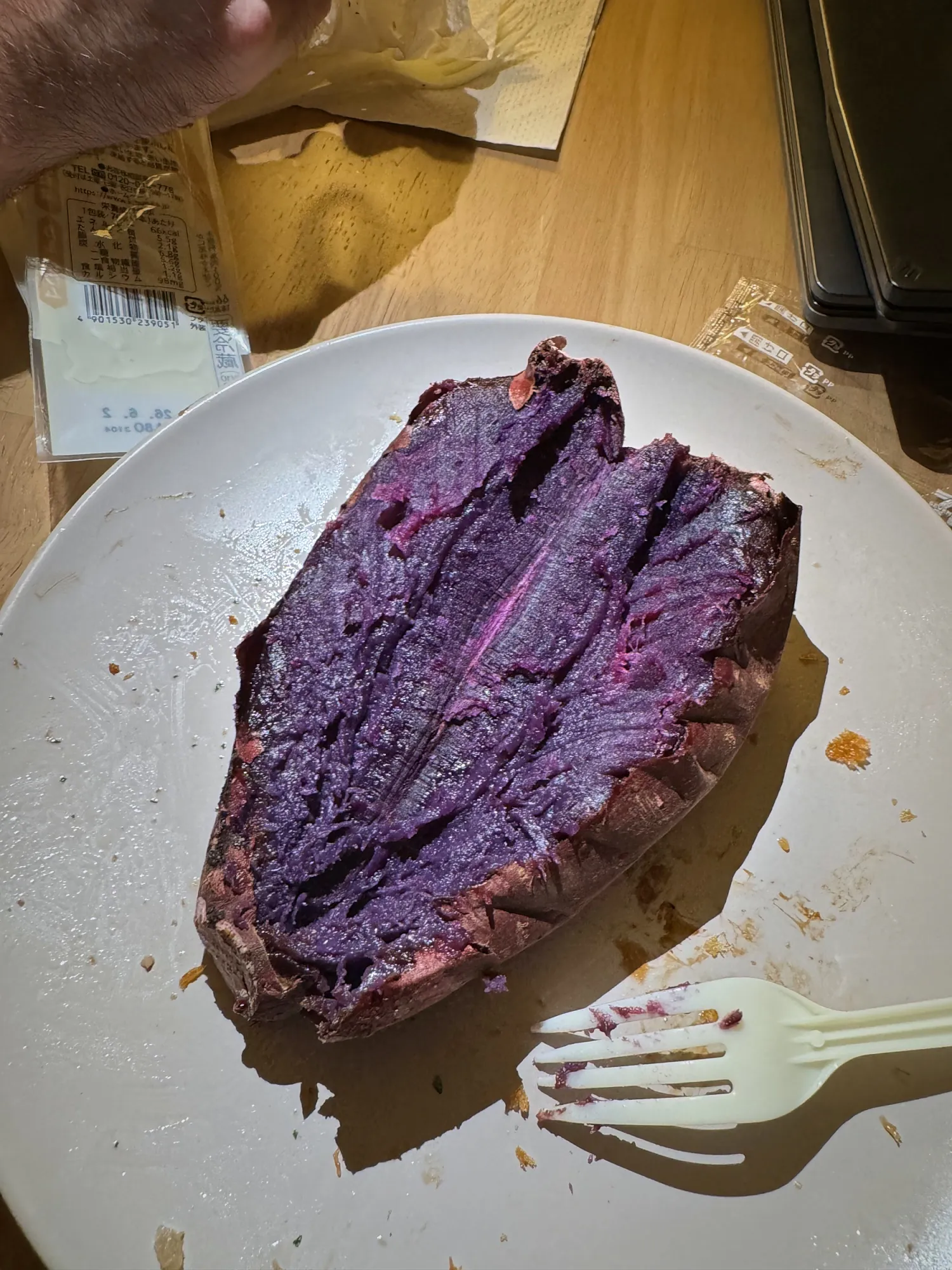 A baked purple sweet potato split open on a white plate, bought at a grocery store in Shinjuku, Tokyo.