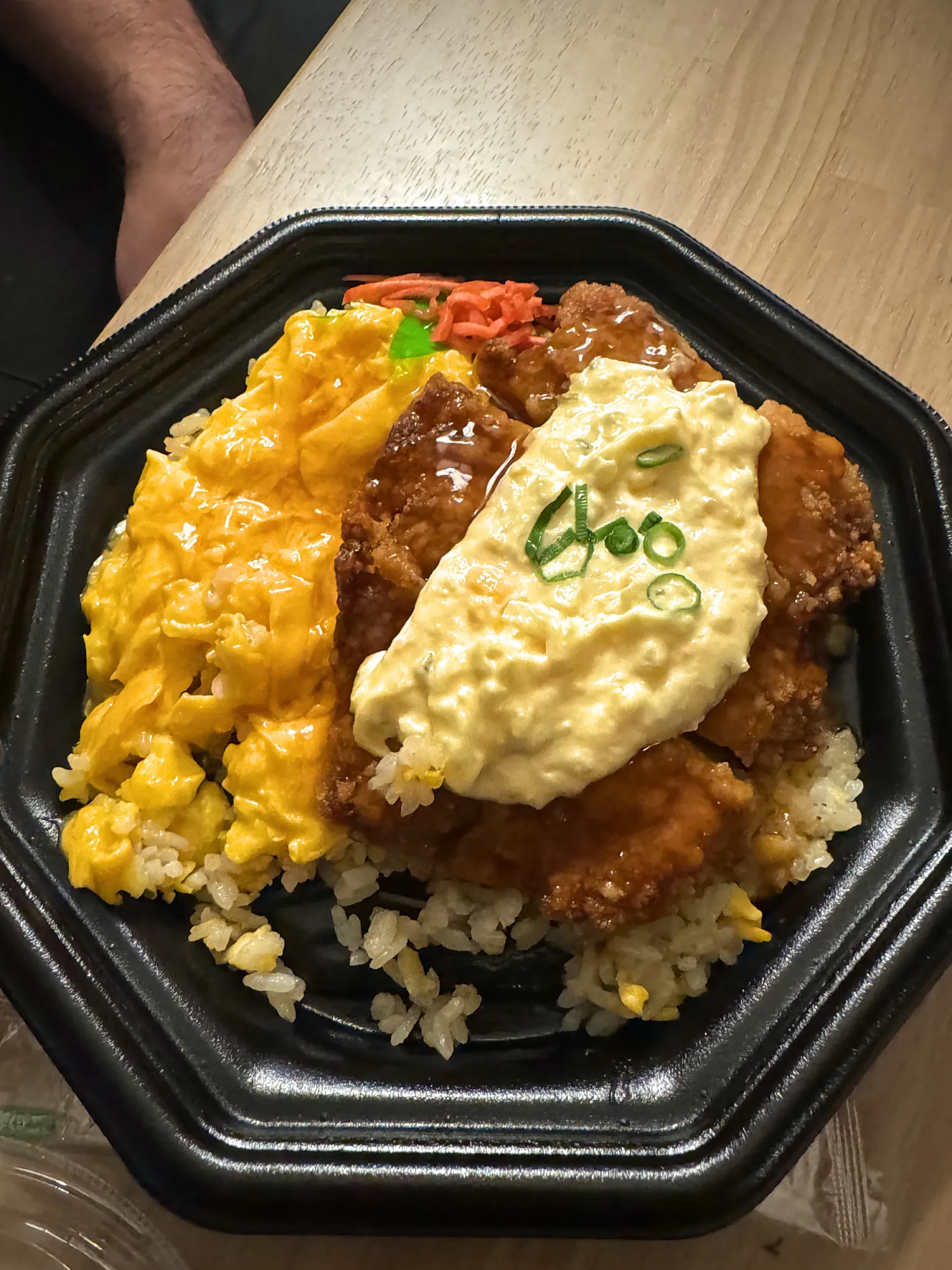 A takeout rice box in Tokyo topped with fried chicken, tartar sauce, scrambled egg, and green onion.