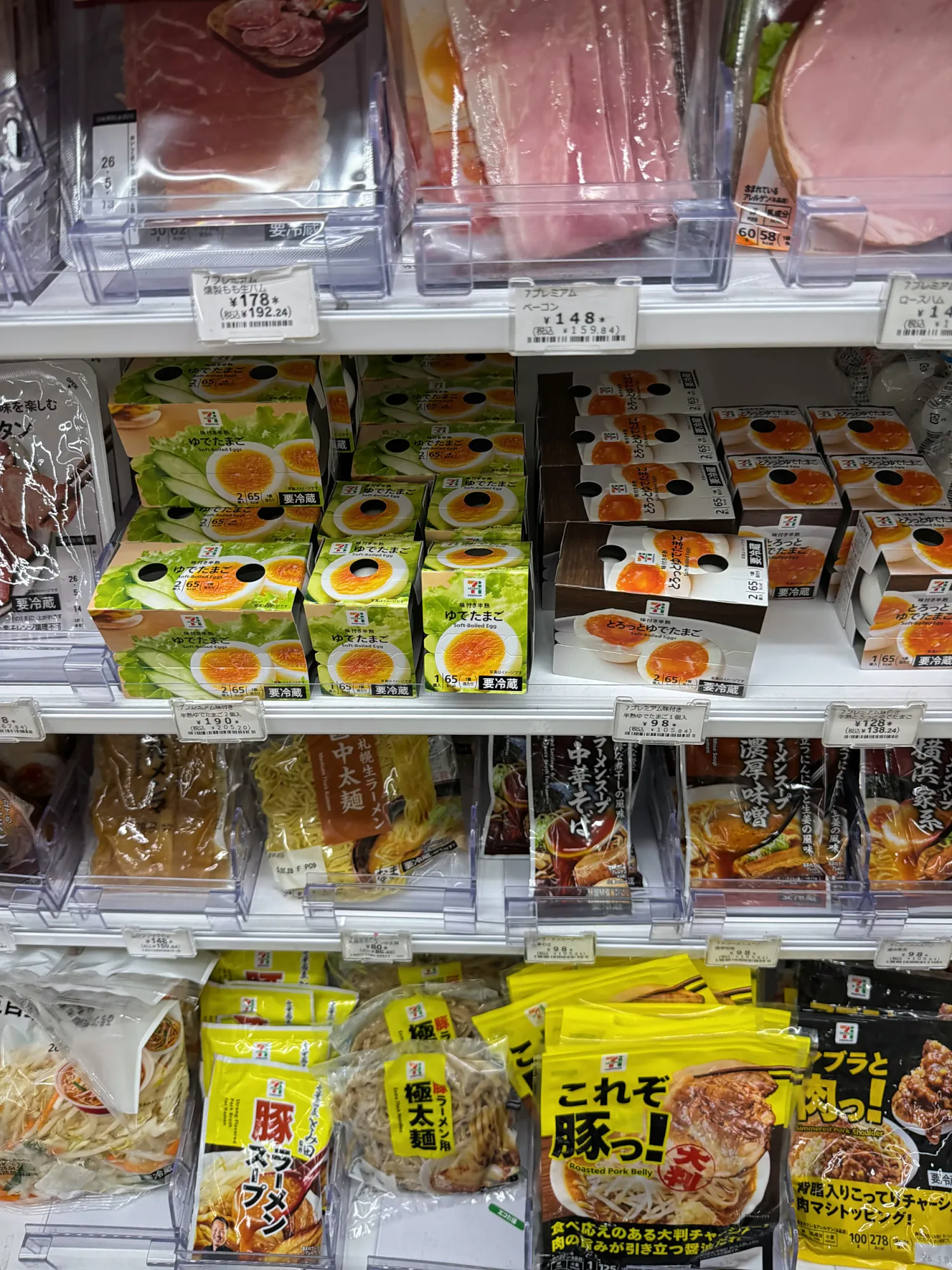 Refrigerated shelves in a Japanese convenience store stocked with packaged eggs, sandwiches, ham, and ready-to-eat snacks.