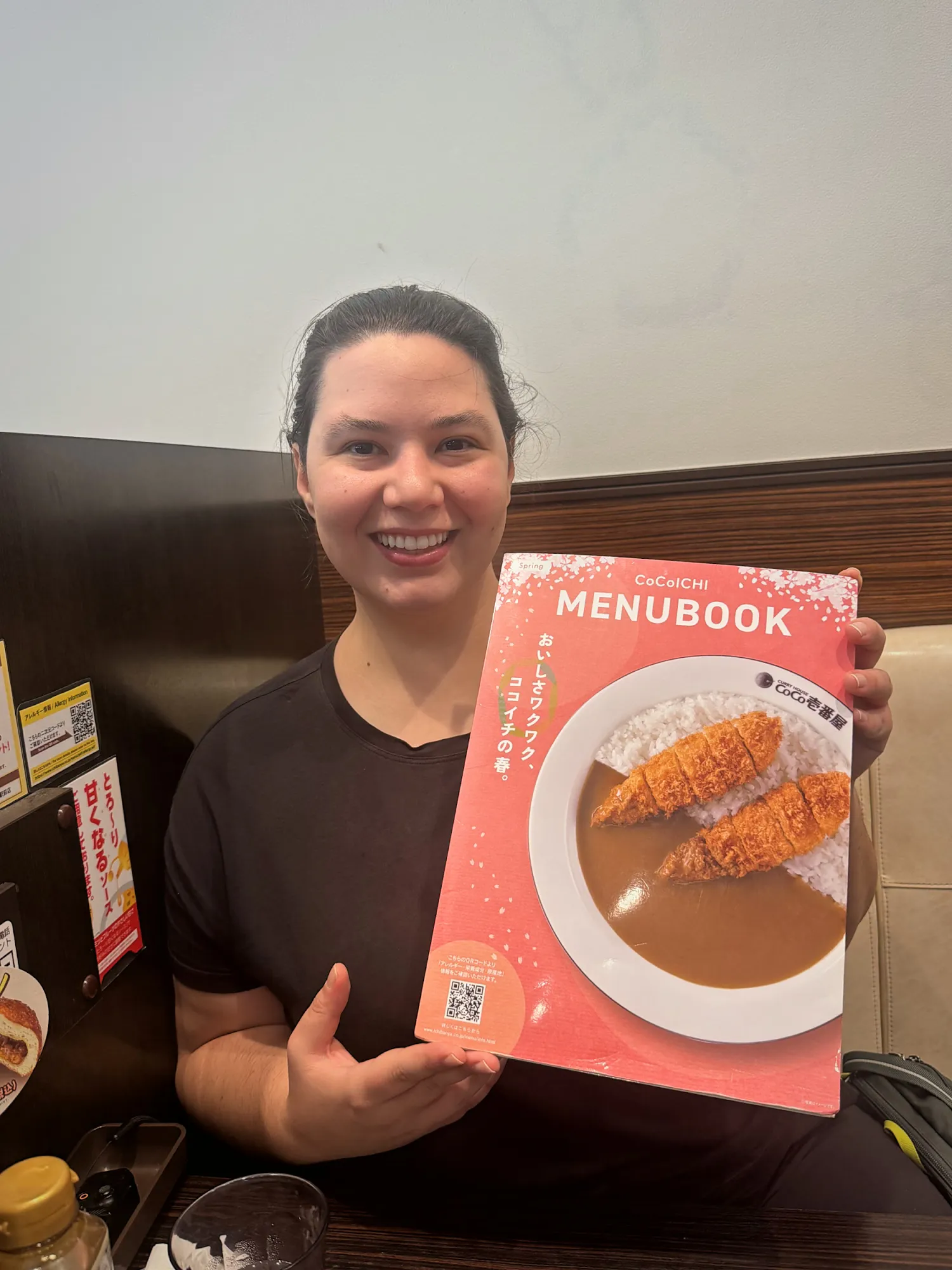 Bernie holding up the English menu book at CoCo Ichibanya in Tokyo, with a pork cutlet curry on the cover.
