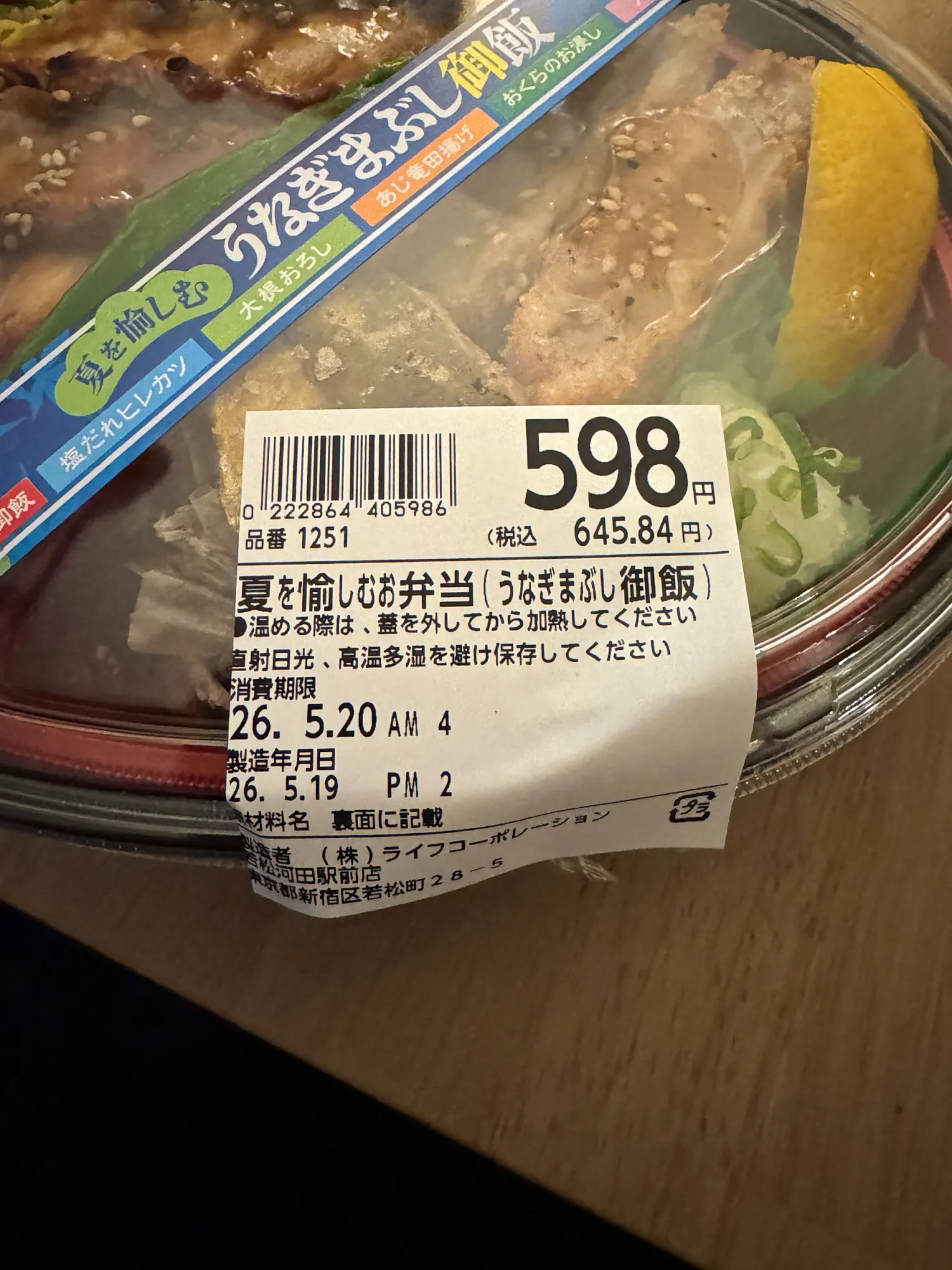 A Japanese supermarket price label on an eel bento showing 598 yen before tax and 645.84 yen including tax.