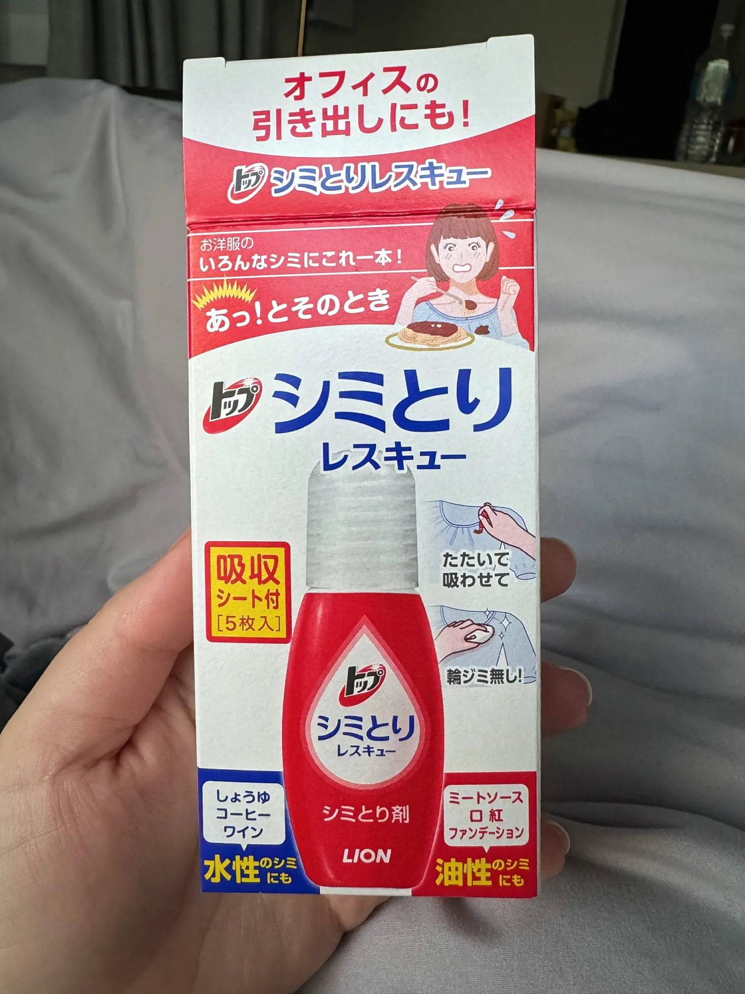 A hand holding a box of Lion stain remover from the cleaning supplies in our Tokyo apartment.