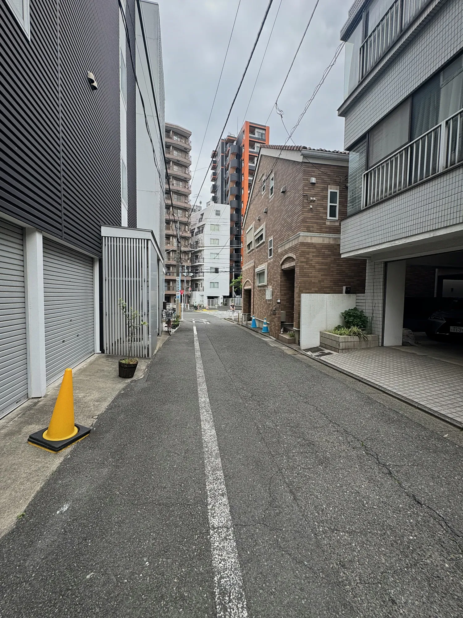 A quiet, narrow residential street in Shinjuku, Tokyo, lined with low apartment buildings.
