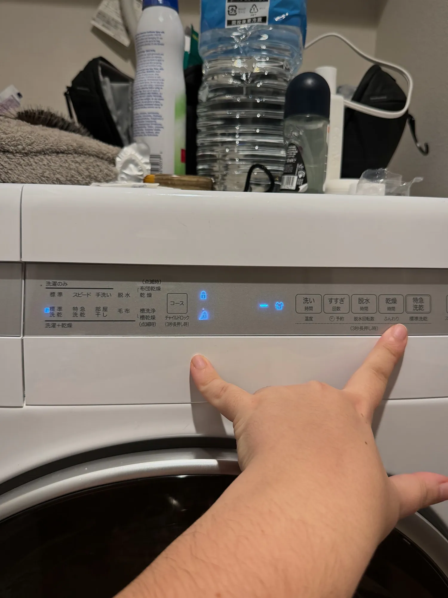 A hand pressing the buttons on the washer-dryer in our monthly Airbnb in Tokyo.