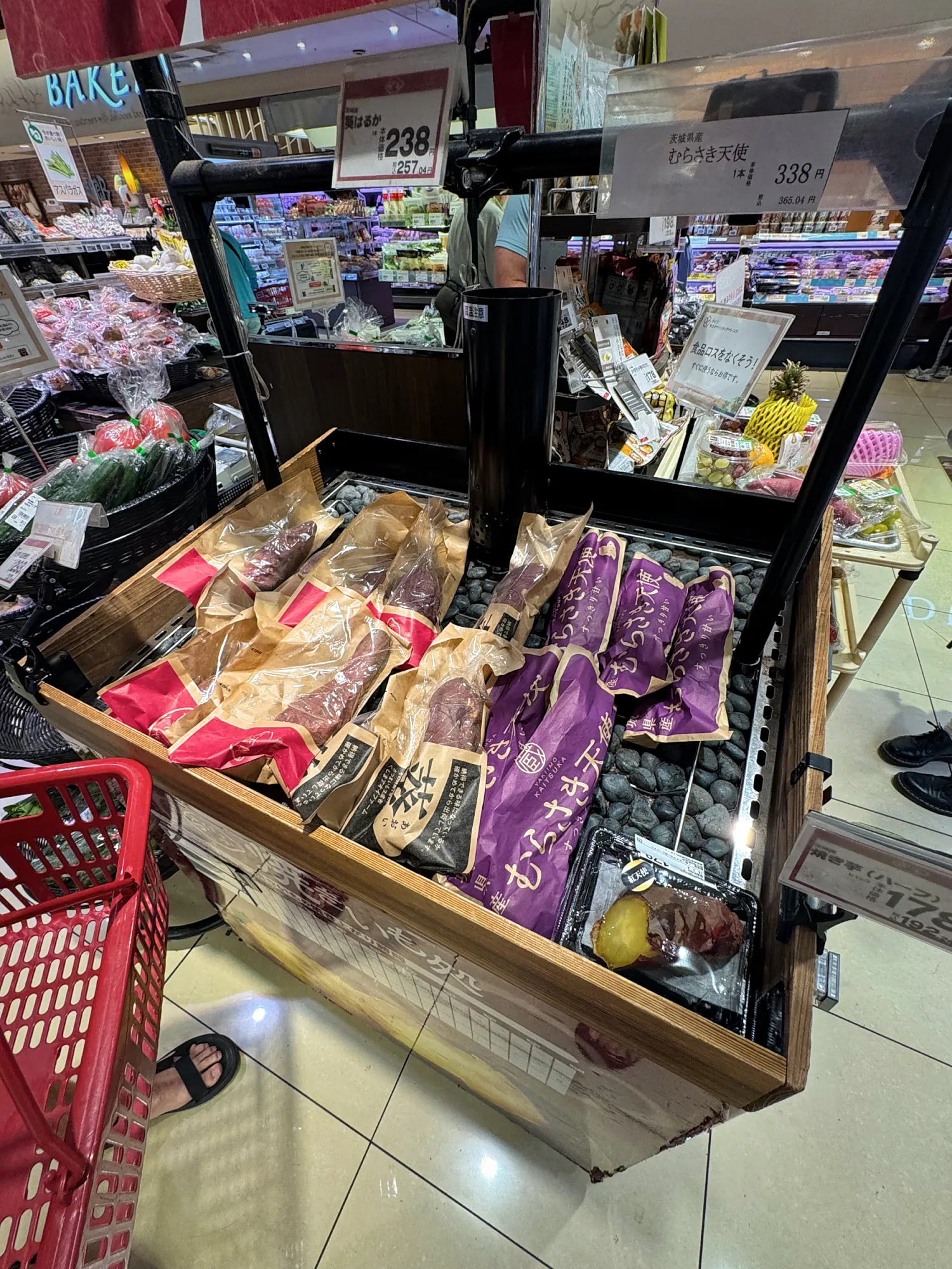 A warm display of roasted sweet potatoes in paper bags, including purple ones, at a Life supermarket in Tokyo