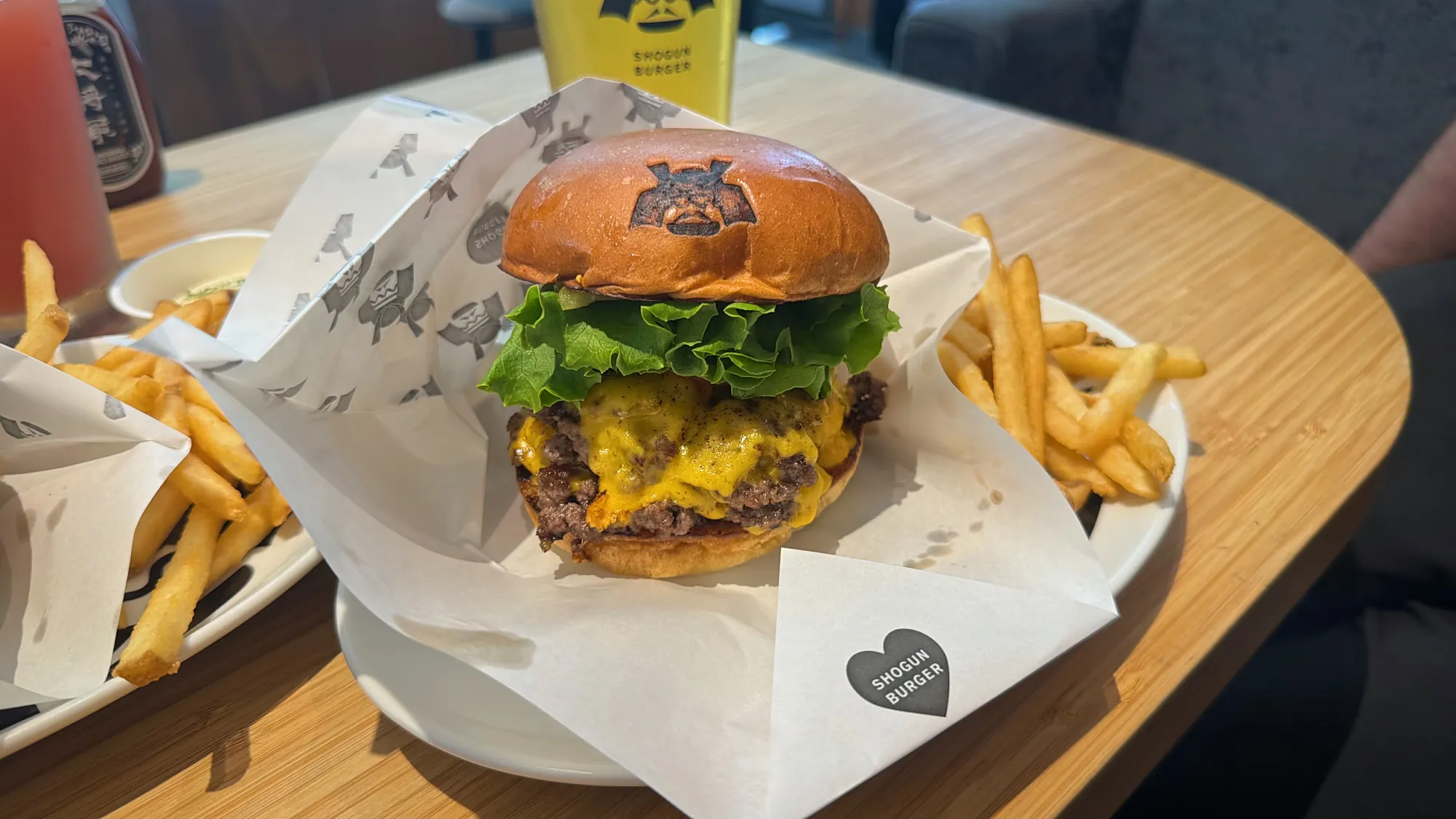 A Shogun Burger double wagyu cheeseburger with fries and a drink on a table in Tokyo.