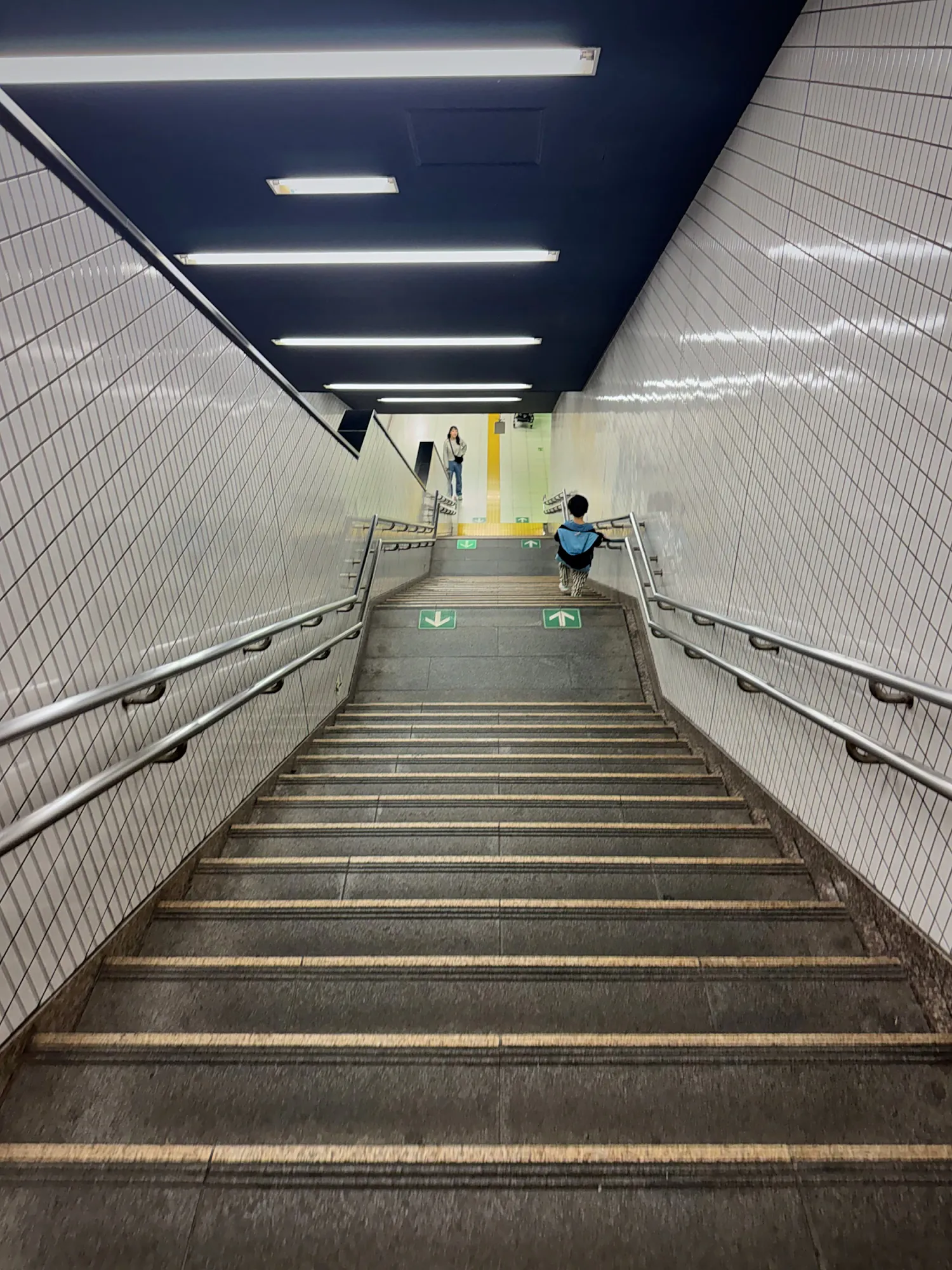 A long, steep staircase leading up from a Tokyo subway platform toward the street.