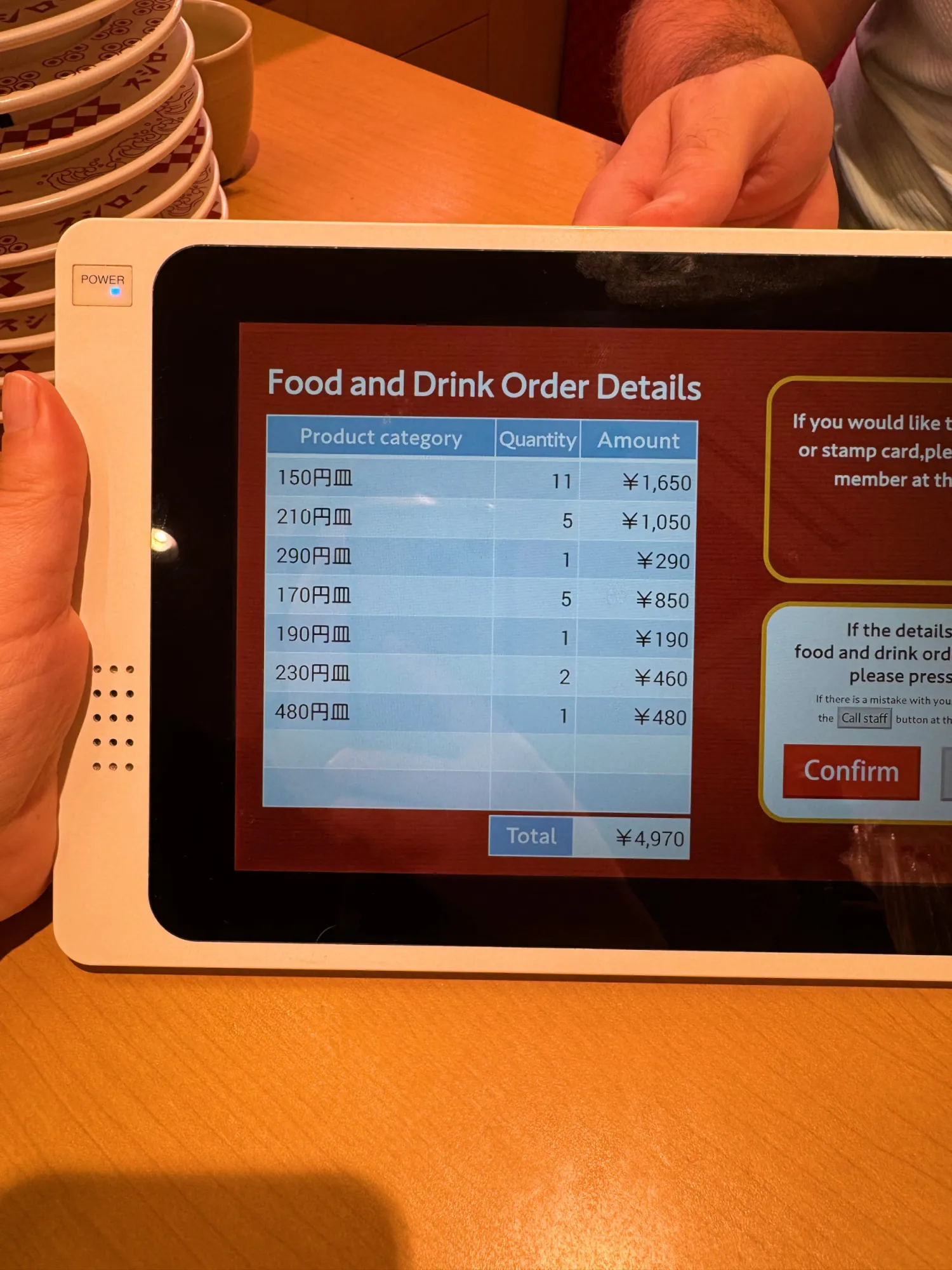The Sushiro tablet's order summary in English, listing plates by price from 150 to 480 yen and a total of 4,970 yen.
