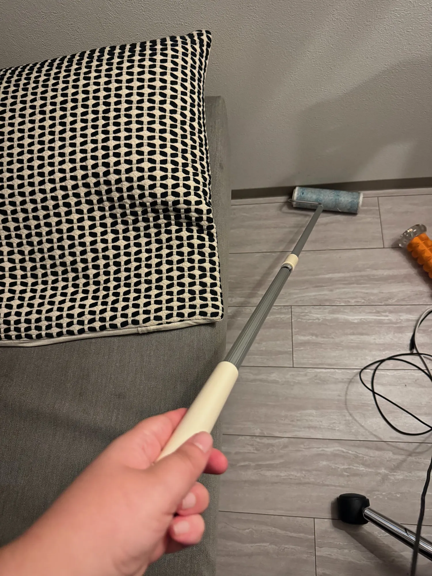 A hand rolling a long-handled sticky lint roller across the floor of our apartment in Tokyo.