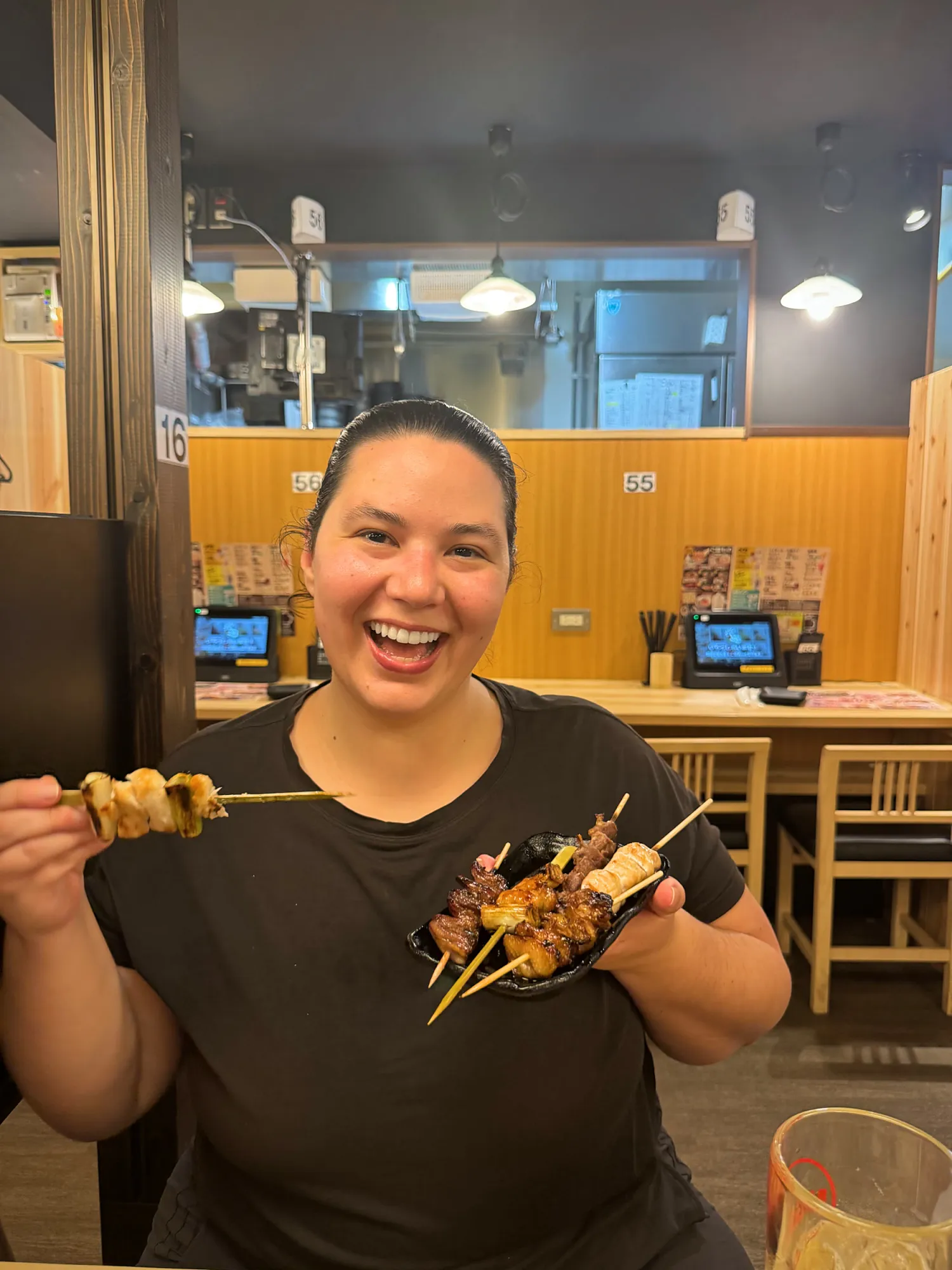 Bernie grinning and holding up a handful of yakitori skewers at Torikizoku