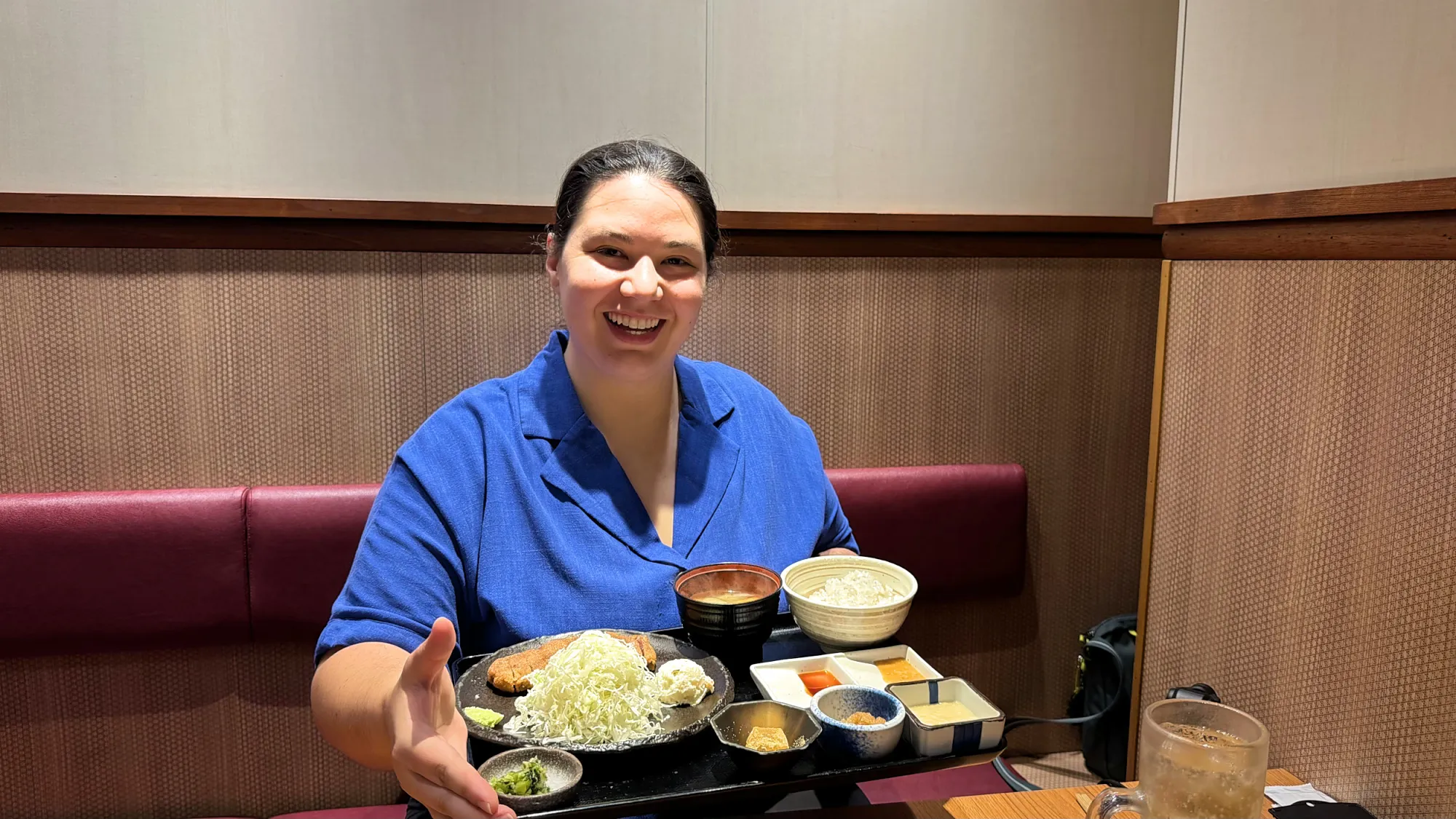 Bernie smiling behind a Gyukatsu Motomura set with the beef cutlet, shredded cabbage, barley rice, soup, and small sides
