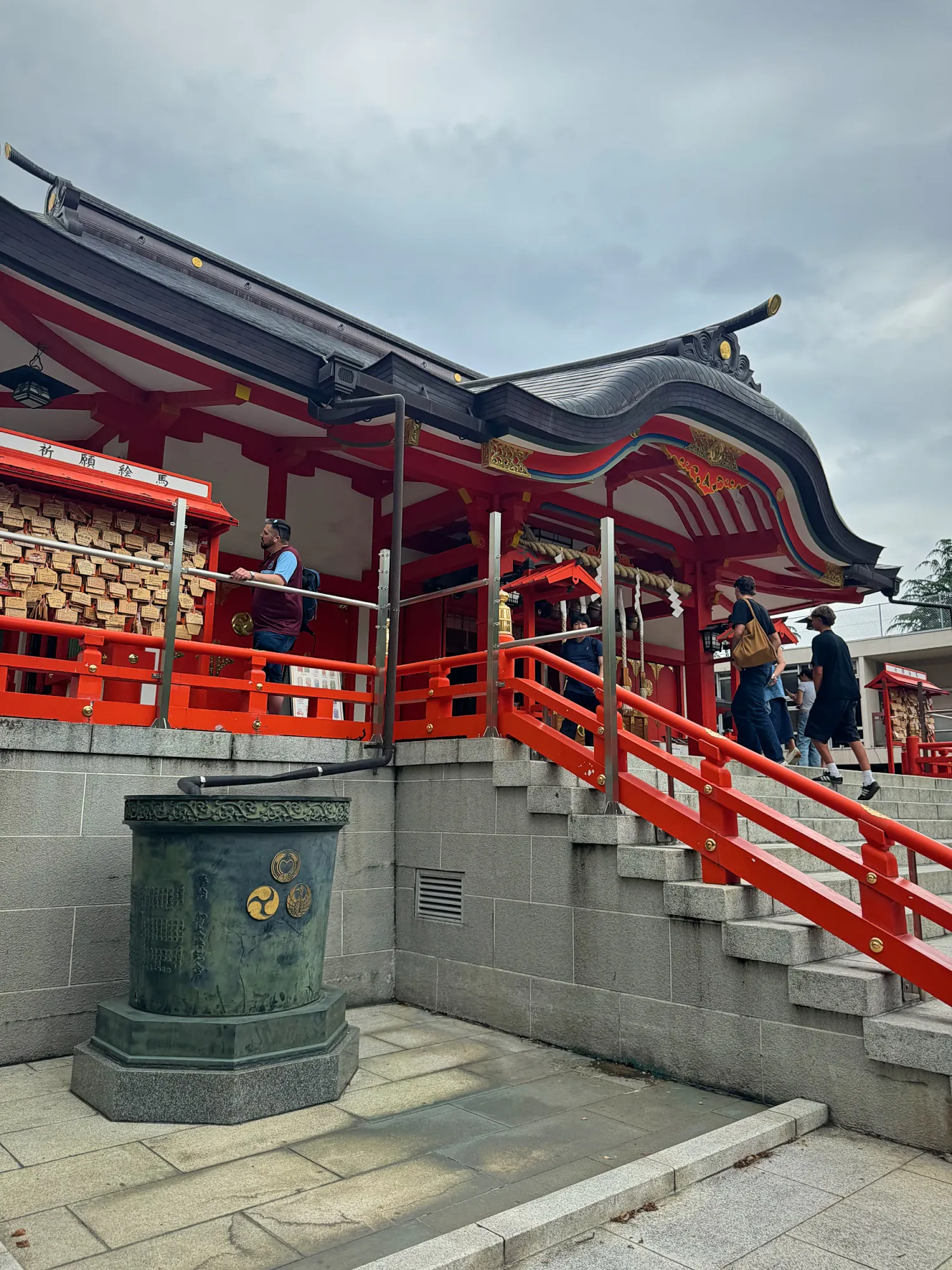 The red main hall and railings of Hanazono Shrine at the top of a stone staircase in Shinjuku, Tokyo.