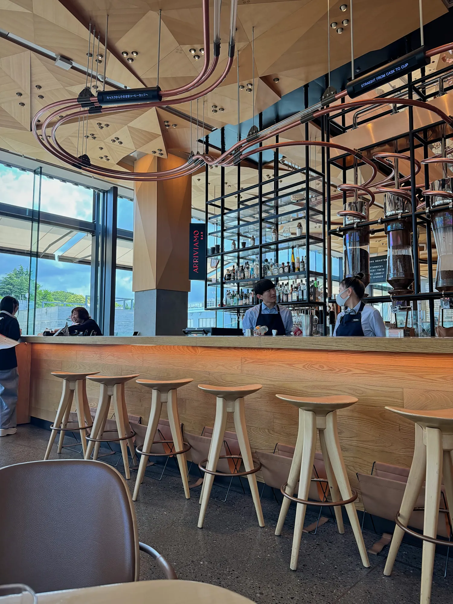 The bar at the Starbucks Reserve Roastery in Nakameguro, Tokyo, with wooden stools and copper coffee equipment.