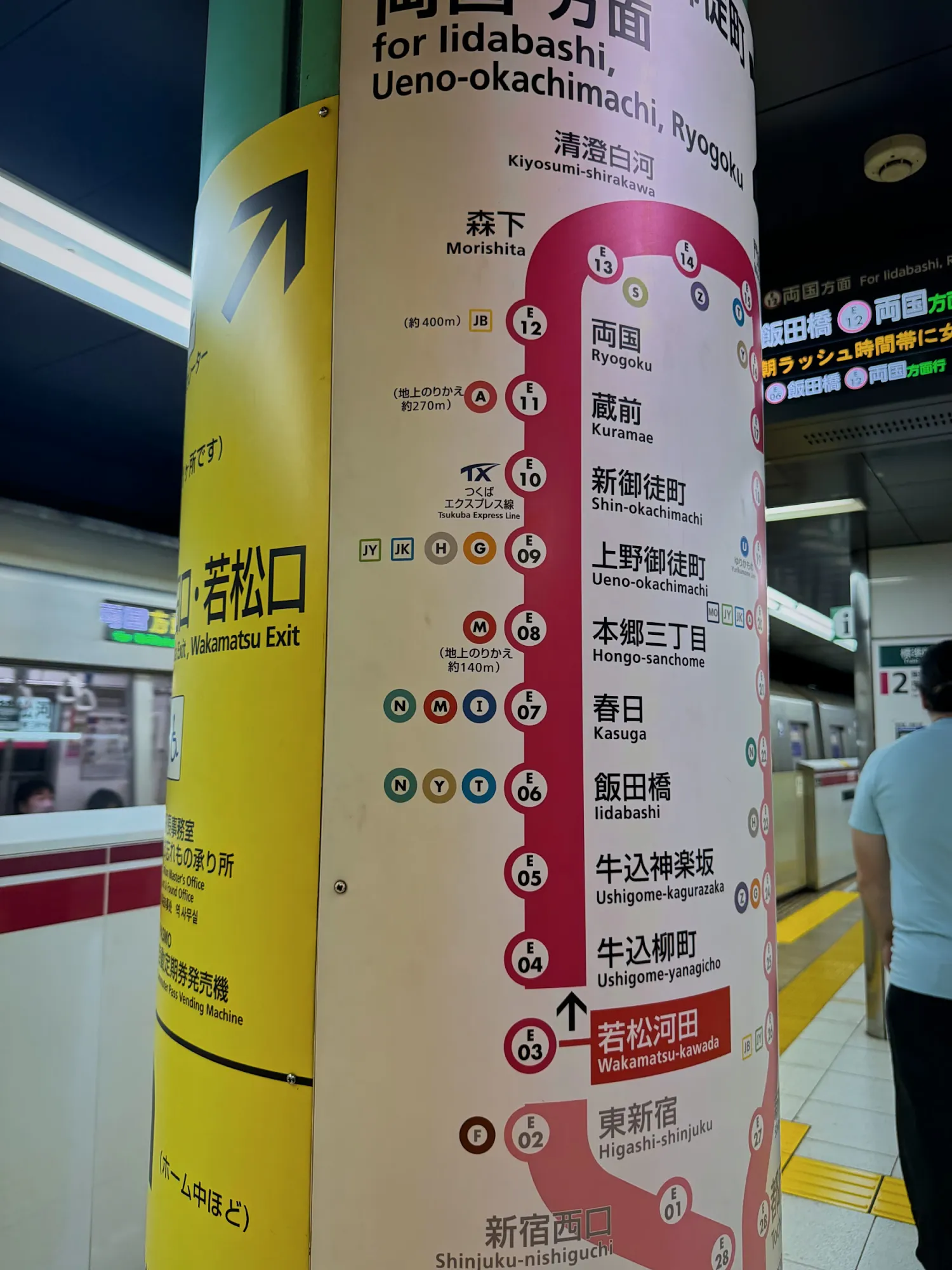 A subway pillar in a Tokyo station showing the line's stops in order, each with its station number.