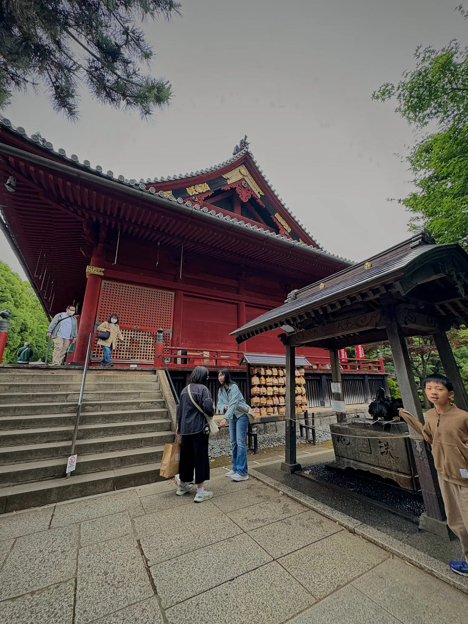Visitors at a red wooden temple hall in Ueno Park, Tokyo.