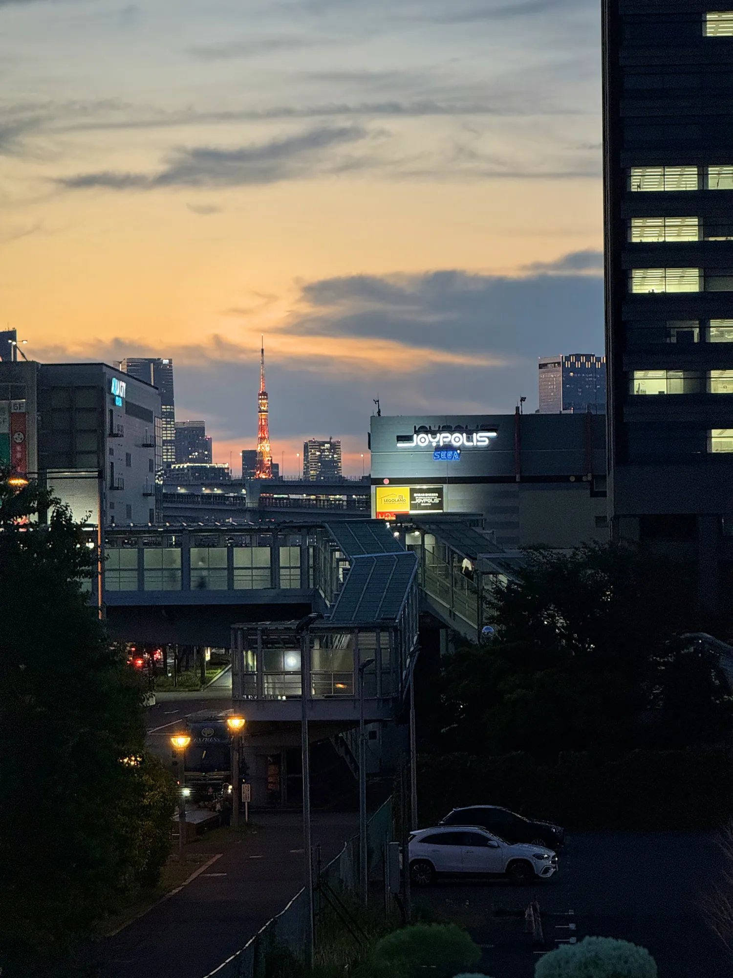 Tokyo Tower glowing on the skyline at dusk under an orange and blue sky.