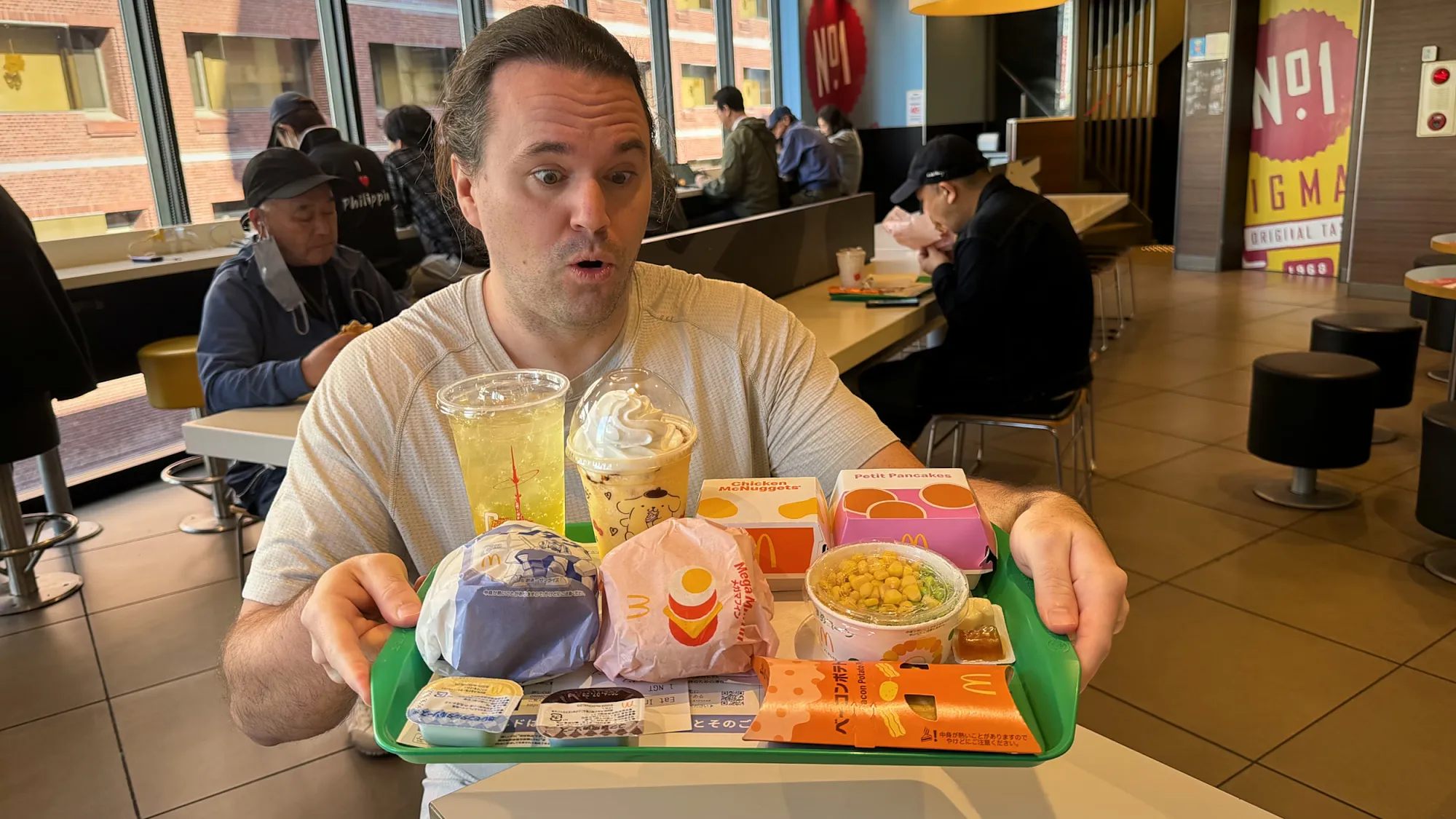 A traveler holding up a tray of McDonald's food and drinks inside a McDonald's in Shinjuku, Tokyo.