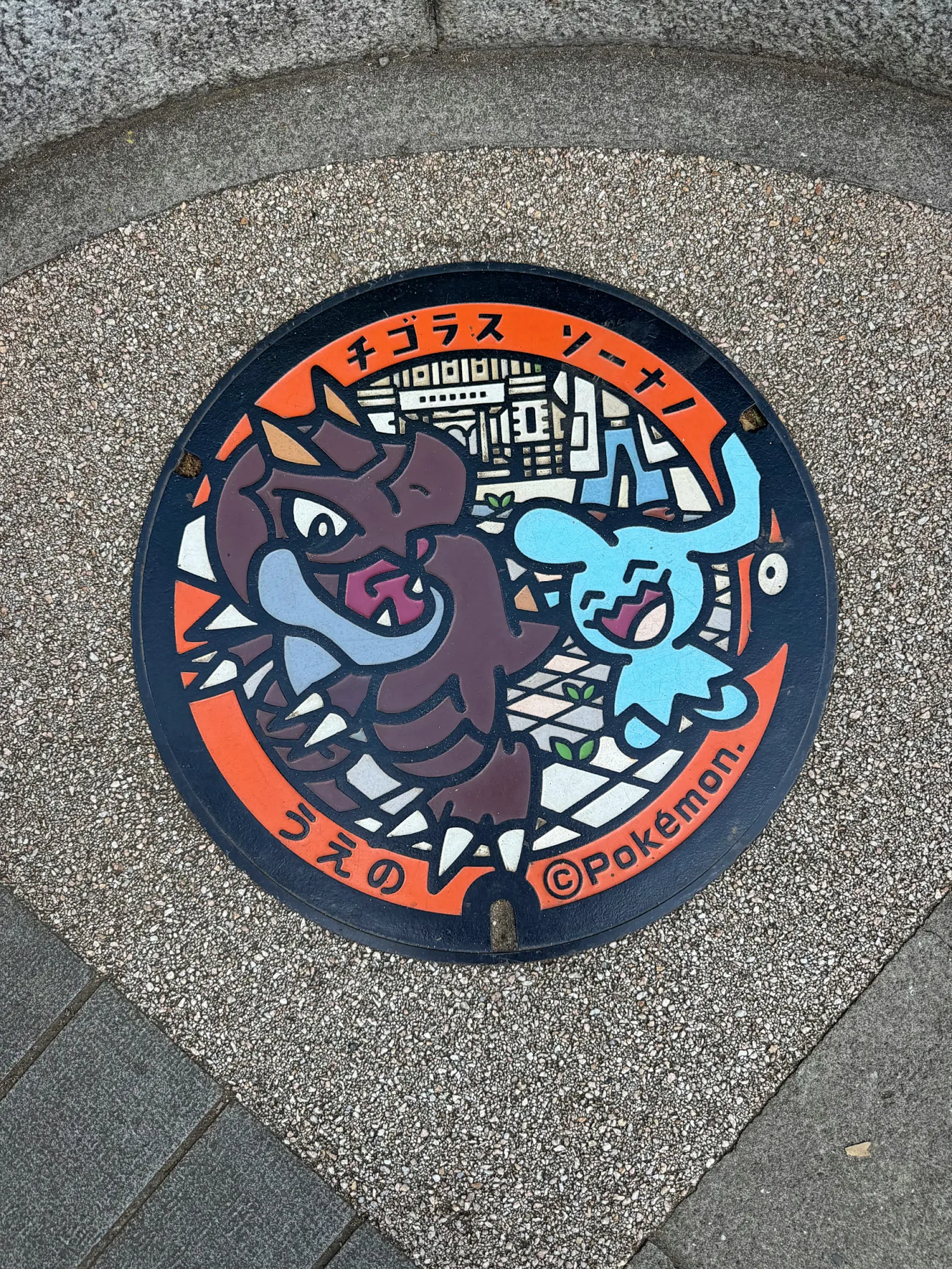 A colorful Pokémon manhole cover with Tyrunt and Wynaut set into the pavement in Ueno Park, Tokyo.