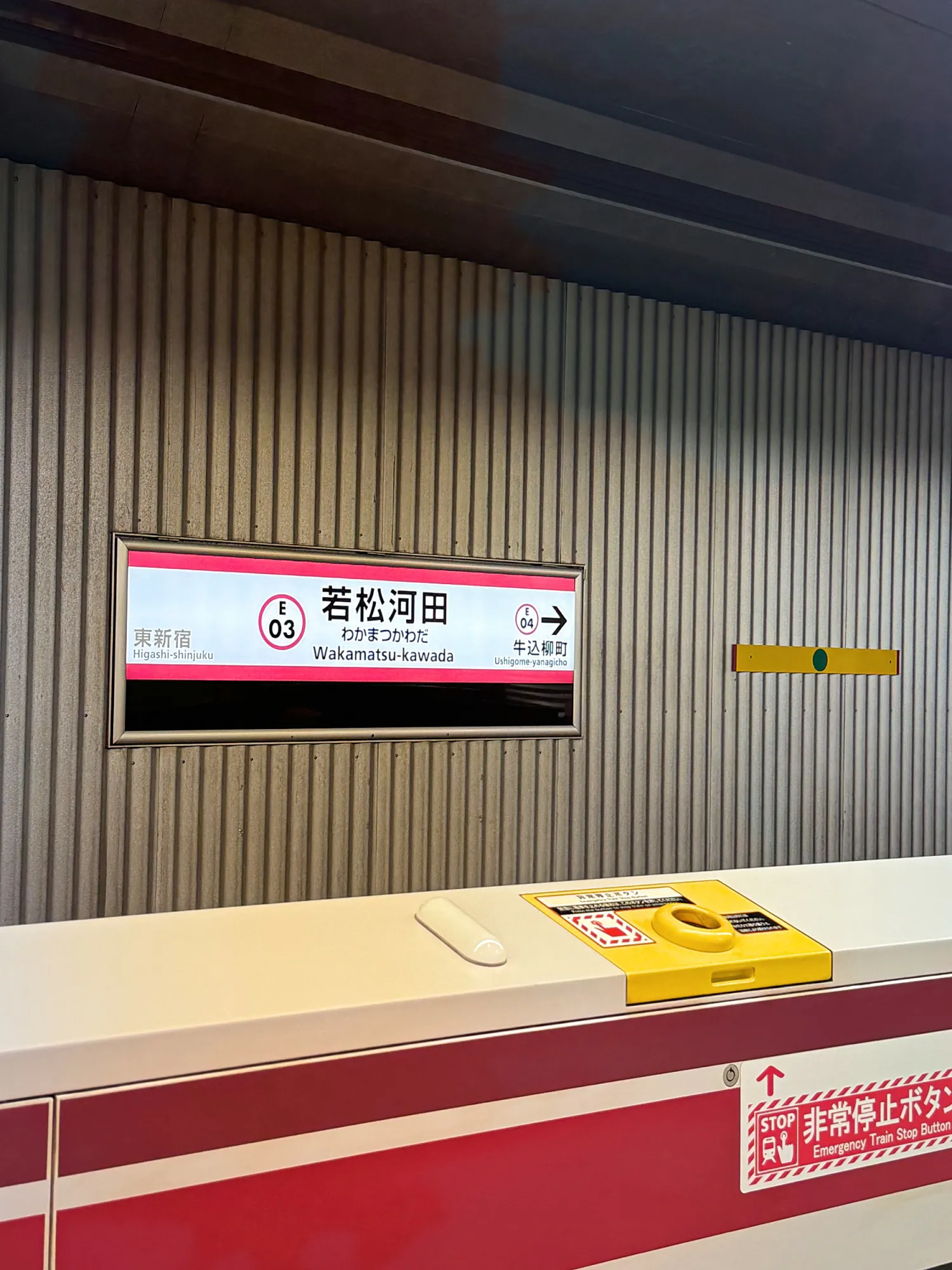 The red and white platform sign for Wakamatsu-Kawada Station on the Toei Oedo Line in Shinjuku, Tokyo.