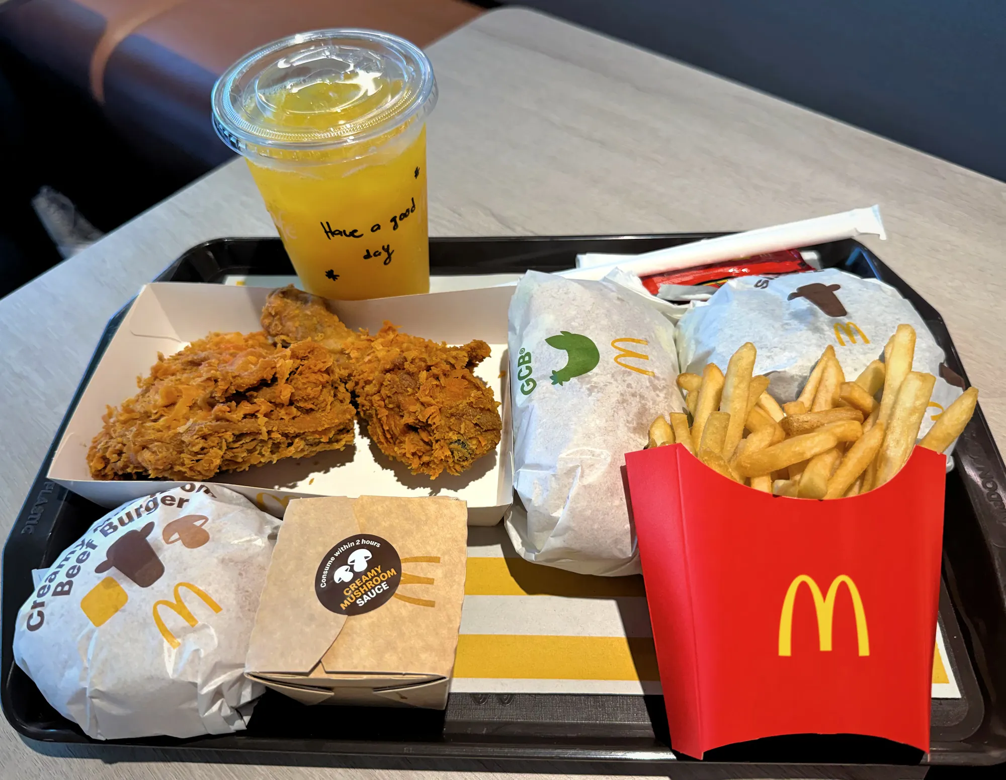 A full McDonald's Malaysia lunch tray filled with golden Ayam Goreng McD fried chicken, burgers, french fries, and an orange drink.
