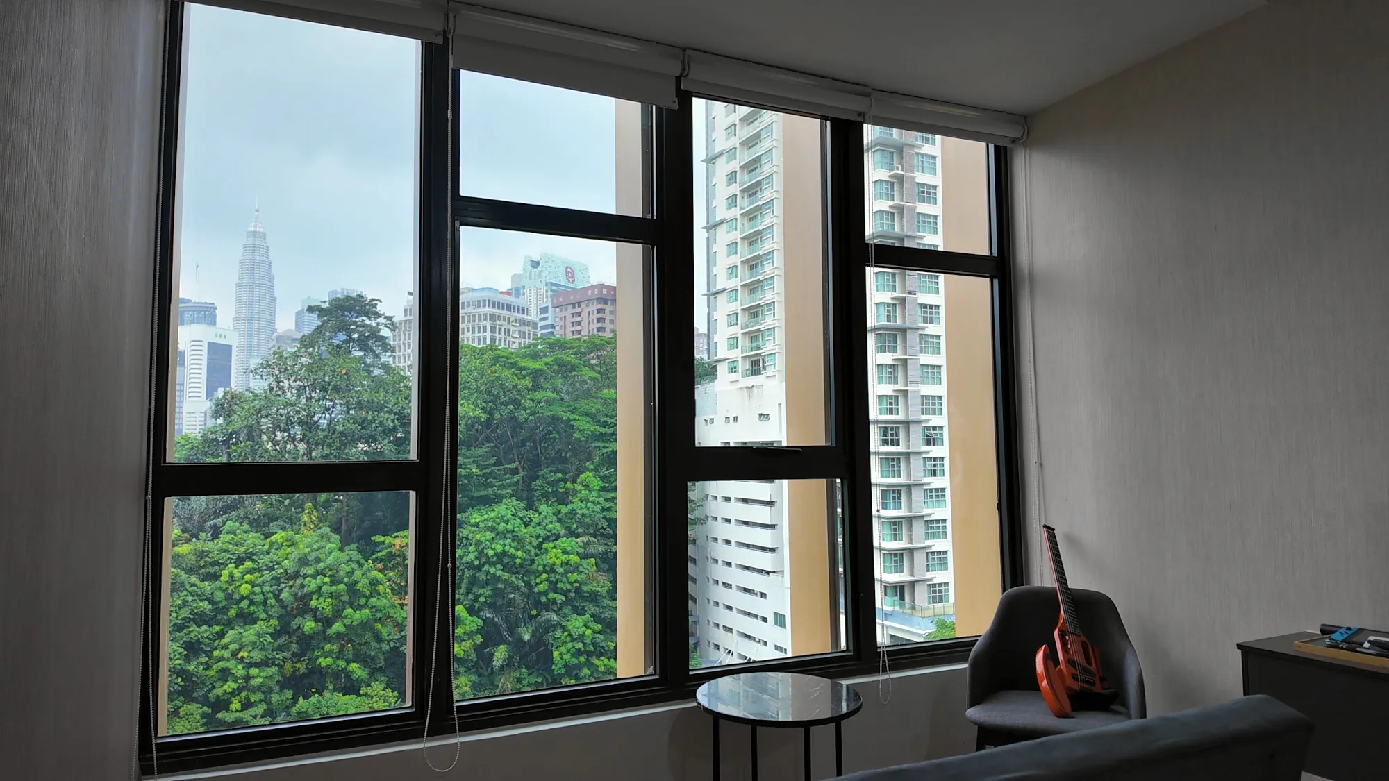 The windows of our studio at Ceylonz Suites looking out over the green trees of KL Forest Eco Park to the city towers.