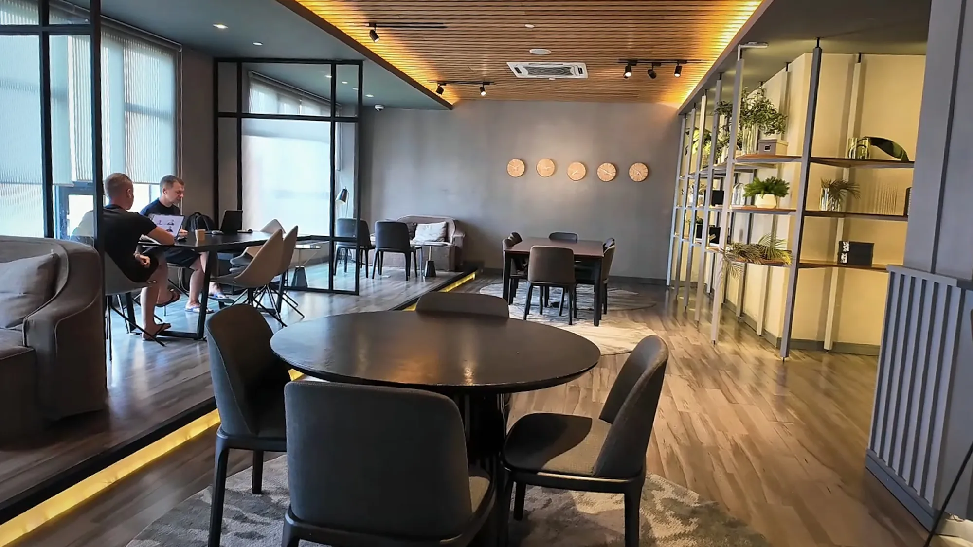 The business lounge at Ceylonz Suites, with round tables, chairs, sofas, and bookshelves.