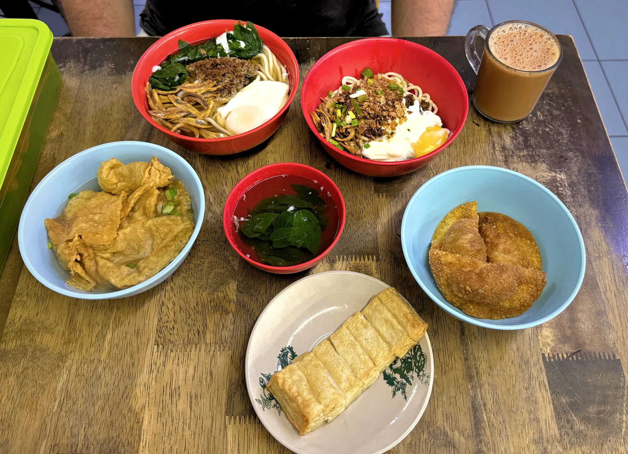 Two bowls of pan mee with sides of fried wontons and fishcake and a glass of teh tarik at Kin Kin in Kuala Lumpur