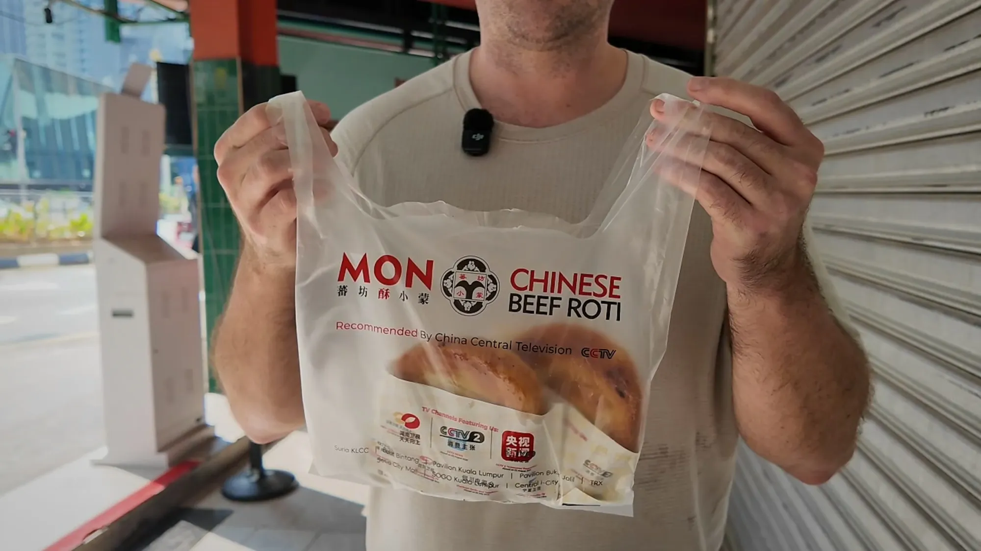 A branded Mon Chinese Beef Roti takeaway bag held up on the street in Kuala Lumpur.