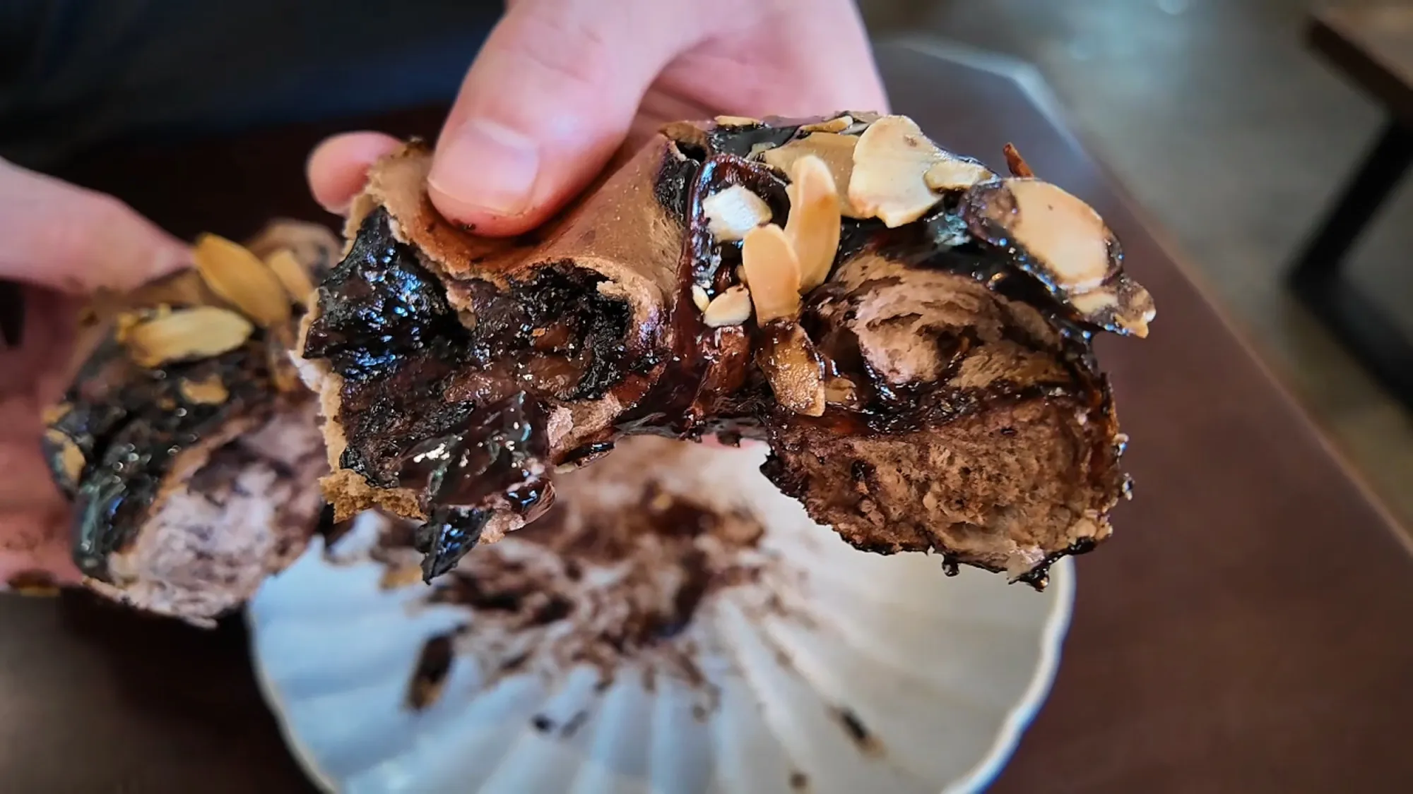 Hands pulling apart the chocolate bagel to show the soft chocolate filling inside.