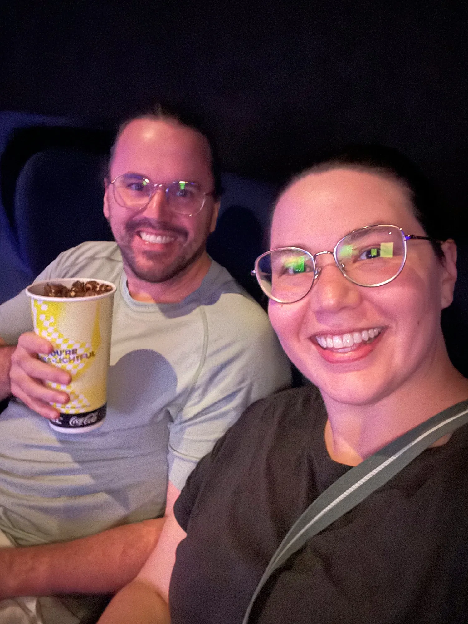 Cream holding a cup of popcorn next to Bernie in a movie-night selfie at Aurum Theatre, The Exchange TRX.