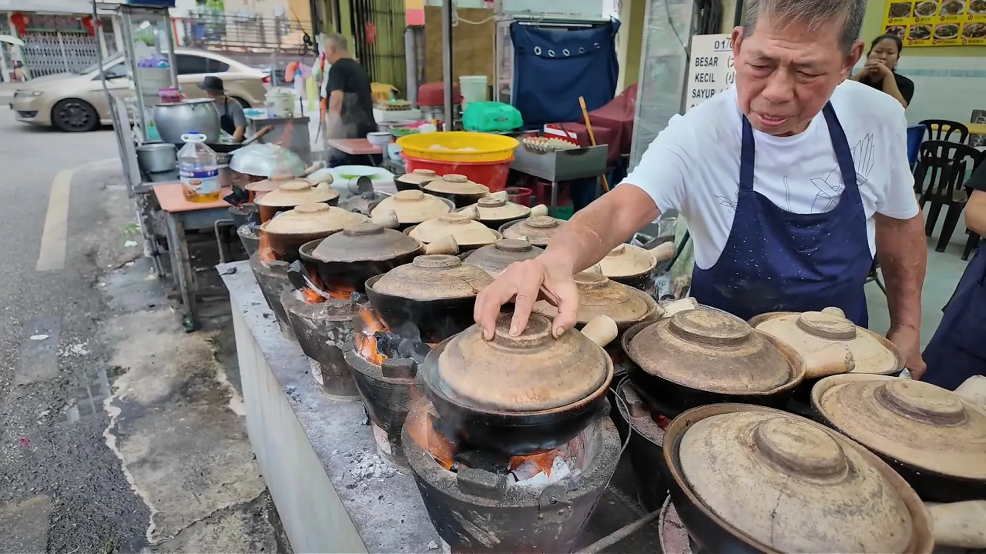 The cook placing a lid on a claypot over charcoal at 168 Claypot Chicken Rice on Jalan Kancil