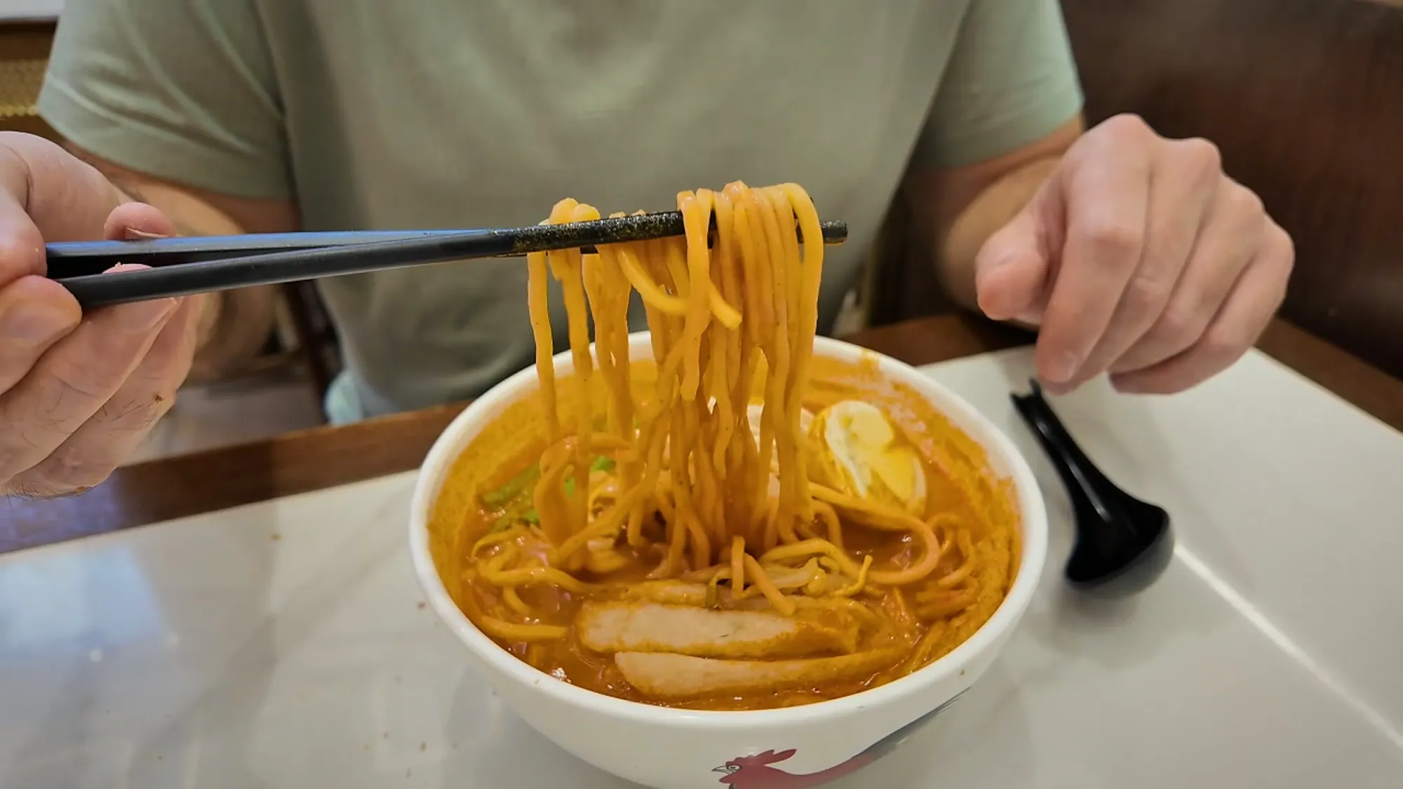 A bowl of curry laksa with chicken, fish cake, and a boiled egg at Oriental Kopi.