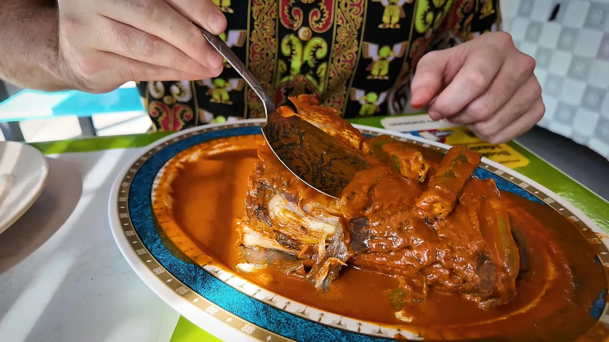 Close up of fish head curry and spoon going into the cheek.