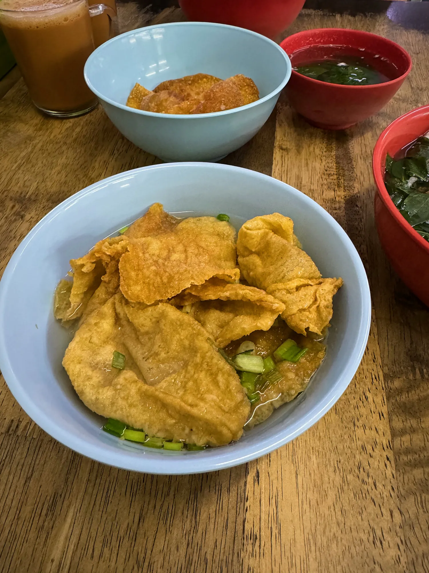 A blue bowl of fried bean curd skin in a little broth with spring onions at Kin Kin, Kuala Lumpur.
