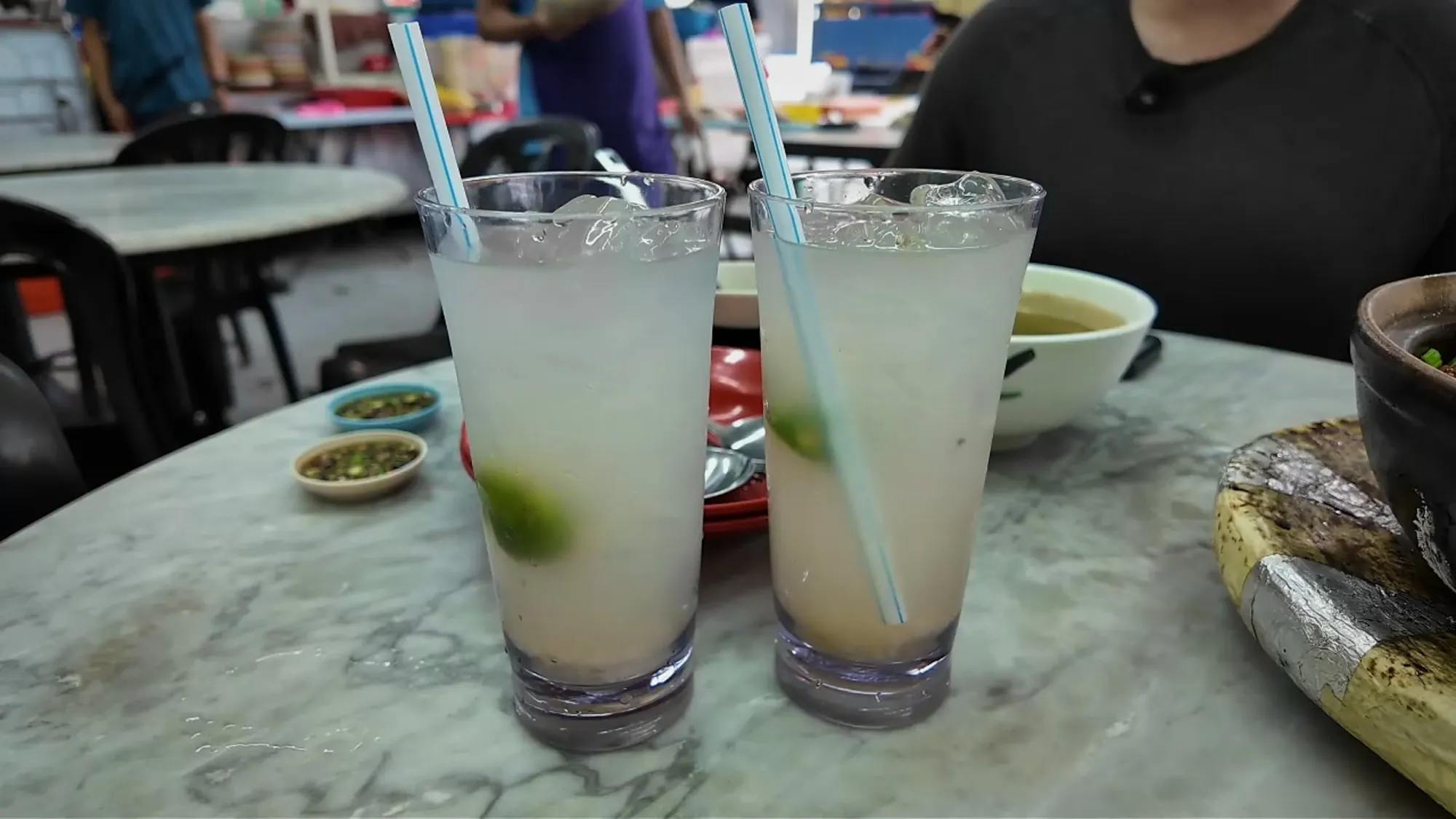 Two glasses of iced barley lime with calamansi on a marble table at 168 Claypot Chicken Rice in Pudu, Kuala Lumpur.
