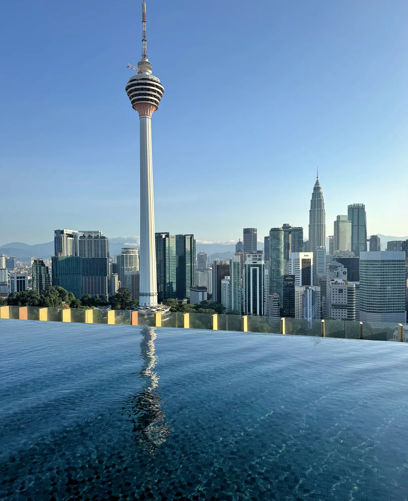 Rooftop infinity pool at Ceylonz Suites in Bukit Bintang, looking out at the KL Tower and the Kuala Lumpur skyline in the morning.
