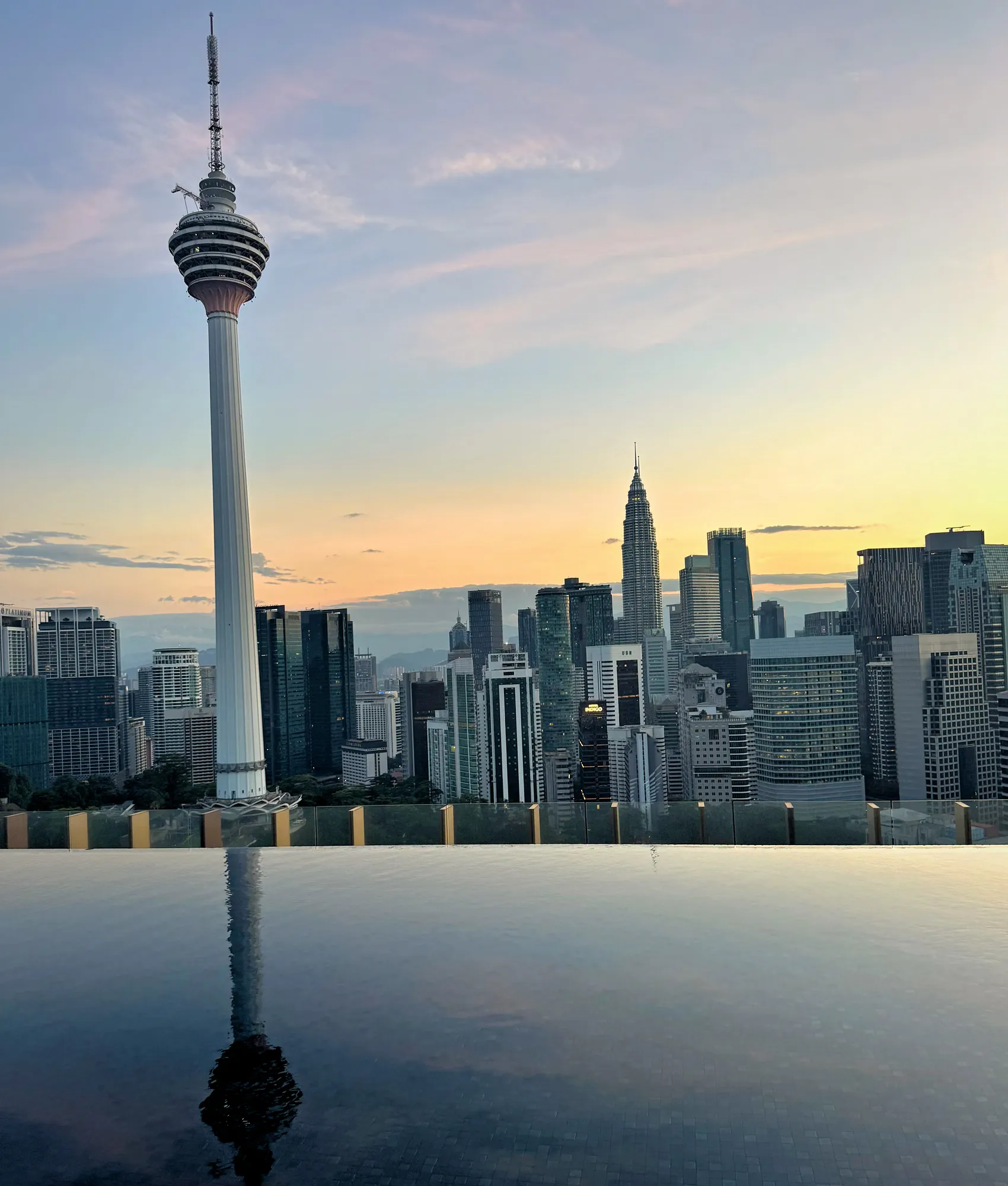The KL Tower and the Kuala Lumpur skyline reflected in a still rooftop infinity pool at sunrise, the kind of view we filtered our monthly Airbnb search for.