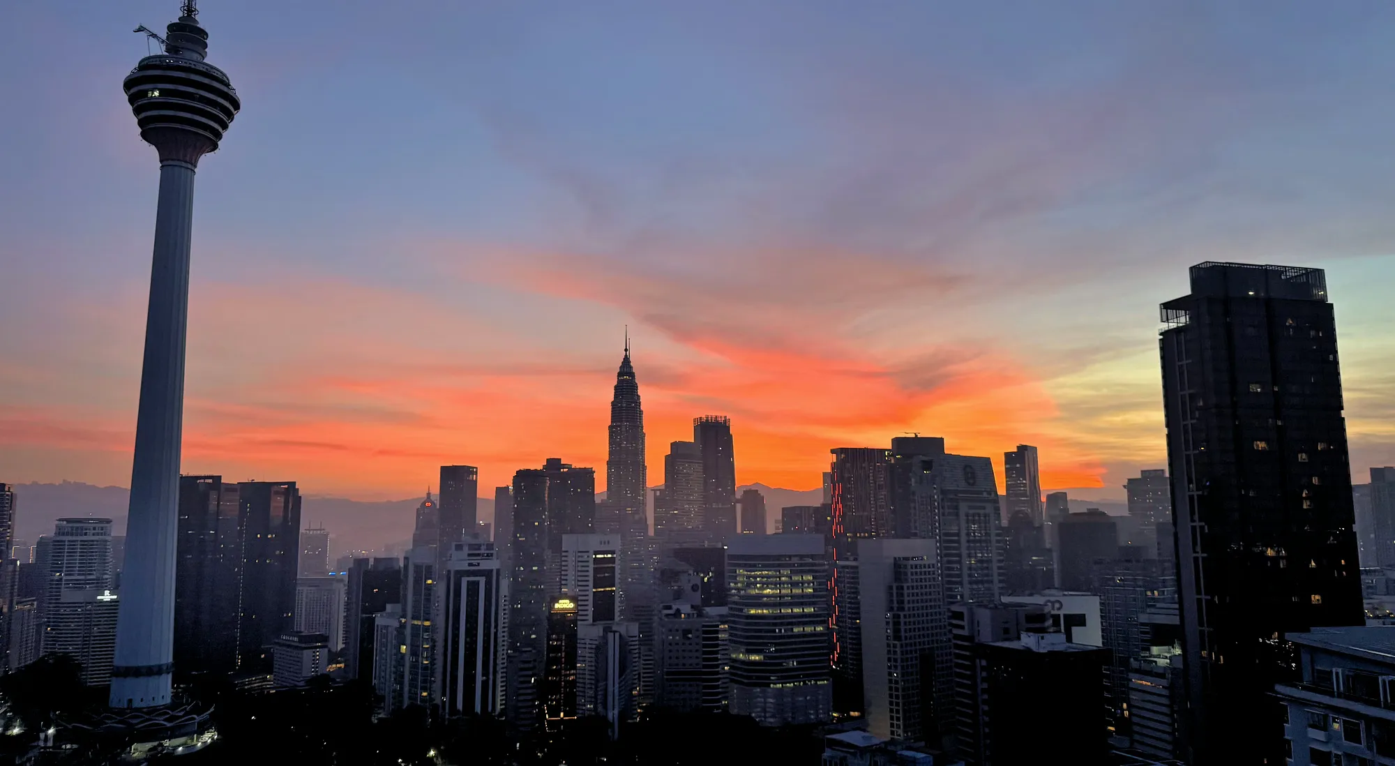 Stunning sunrise view of the Kuala Lumpur skyline featuring the KL Tower and Petronas Towers.