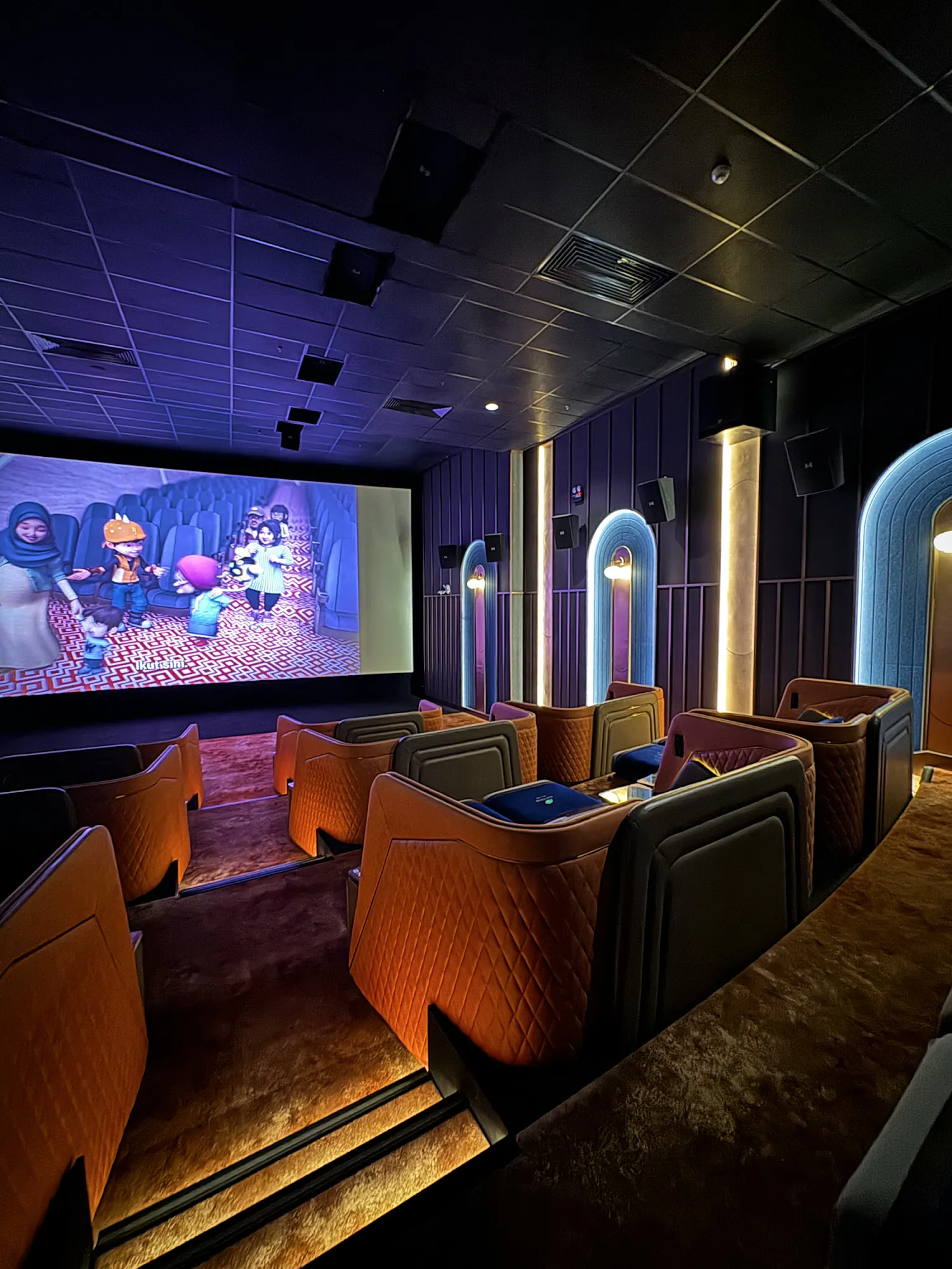 Rows of orange bed-style recliner pods facing the screen in a Getha Lux Suite at Aurum Theatre, The Exchange TRX.