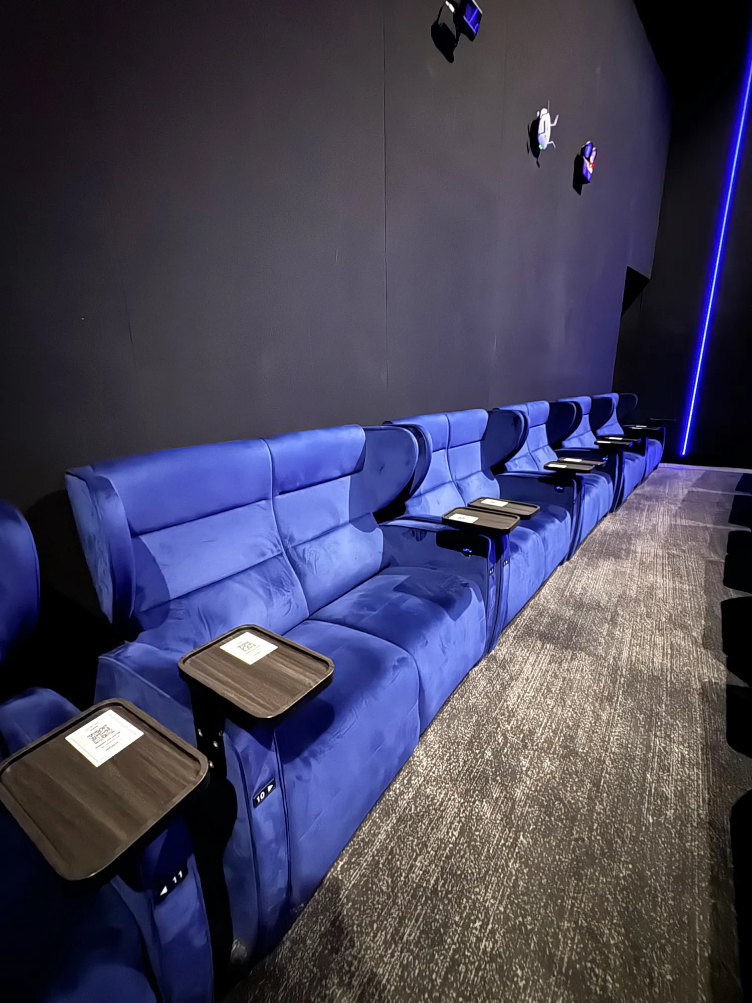 Empty rows of blue velvet recliners with small wooden tray tables in the IMAX hall at Aurum Theatre, The Exchange TRX, one of the best cinemas in Kuala Lumpur.