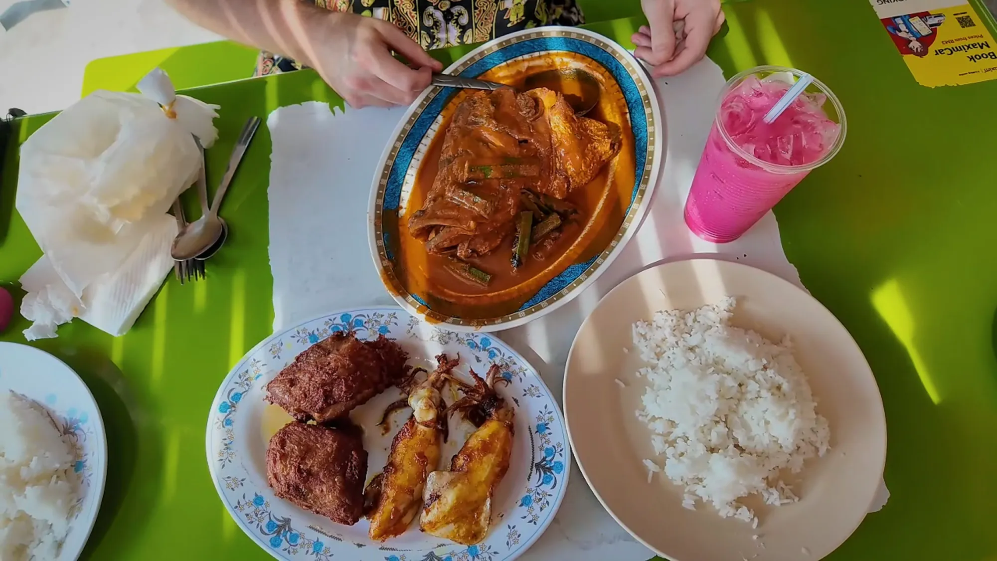 Our table at Anuar's: fish head curry with okra, fried chicken and squid, white rice, and a tall pink sirap bandung on a green table in Bangsar, Kuala Lumpur.