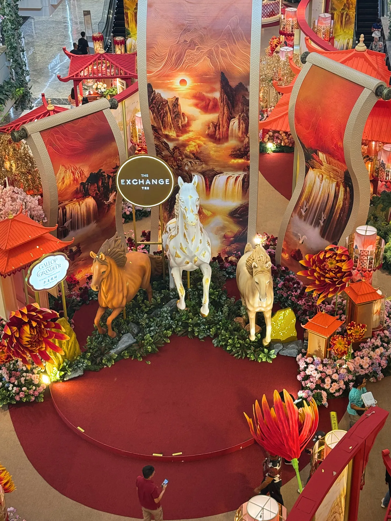 Three horse statues on a red stage in front of giant painted scrolls, a Year of the Horse display at The Exchange TRX in Kuala Lumpur.