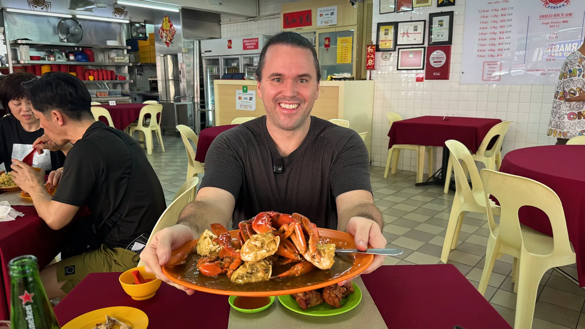 Cream smiling and holding up a plate of sweet and sour chilli crab at Fatty Crab, Petaling Jaya.